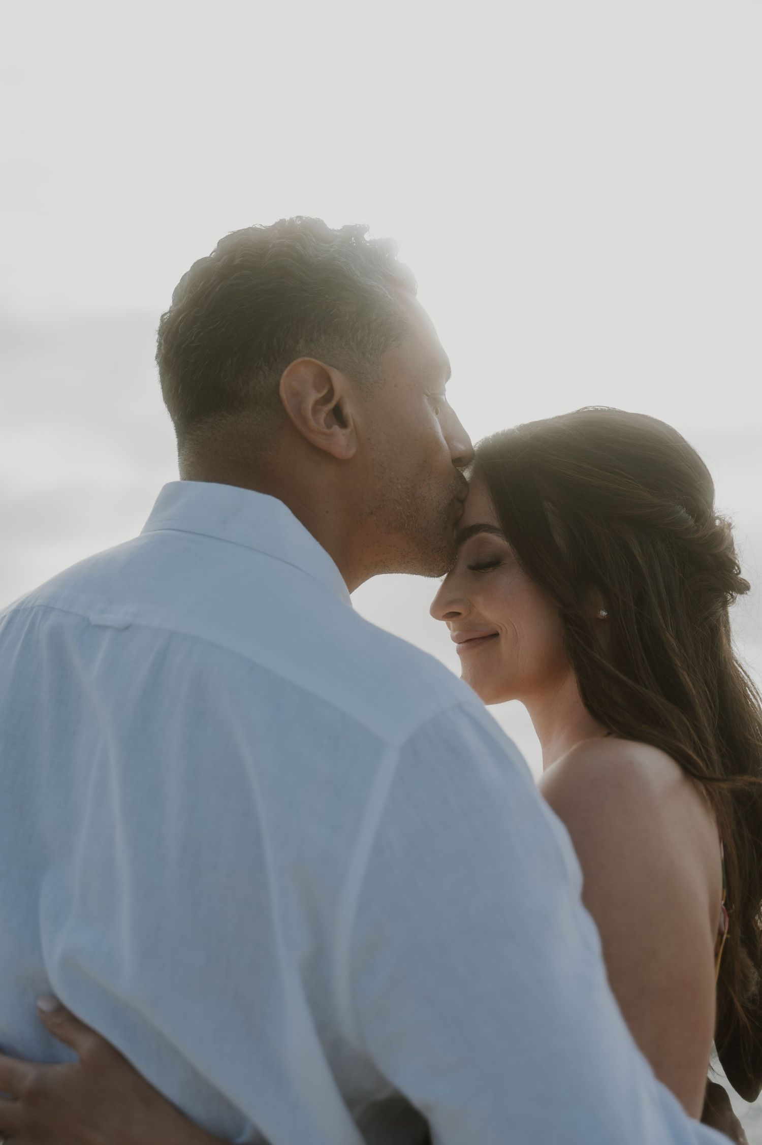 Soft, dreamy silhouette of couple embracing during golden hour wedding photography.