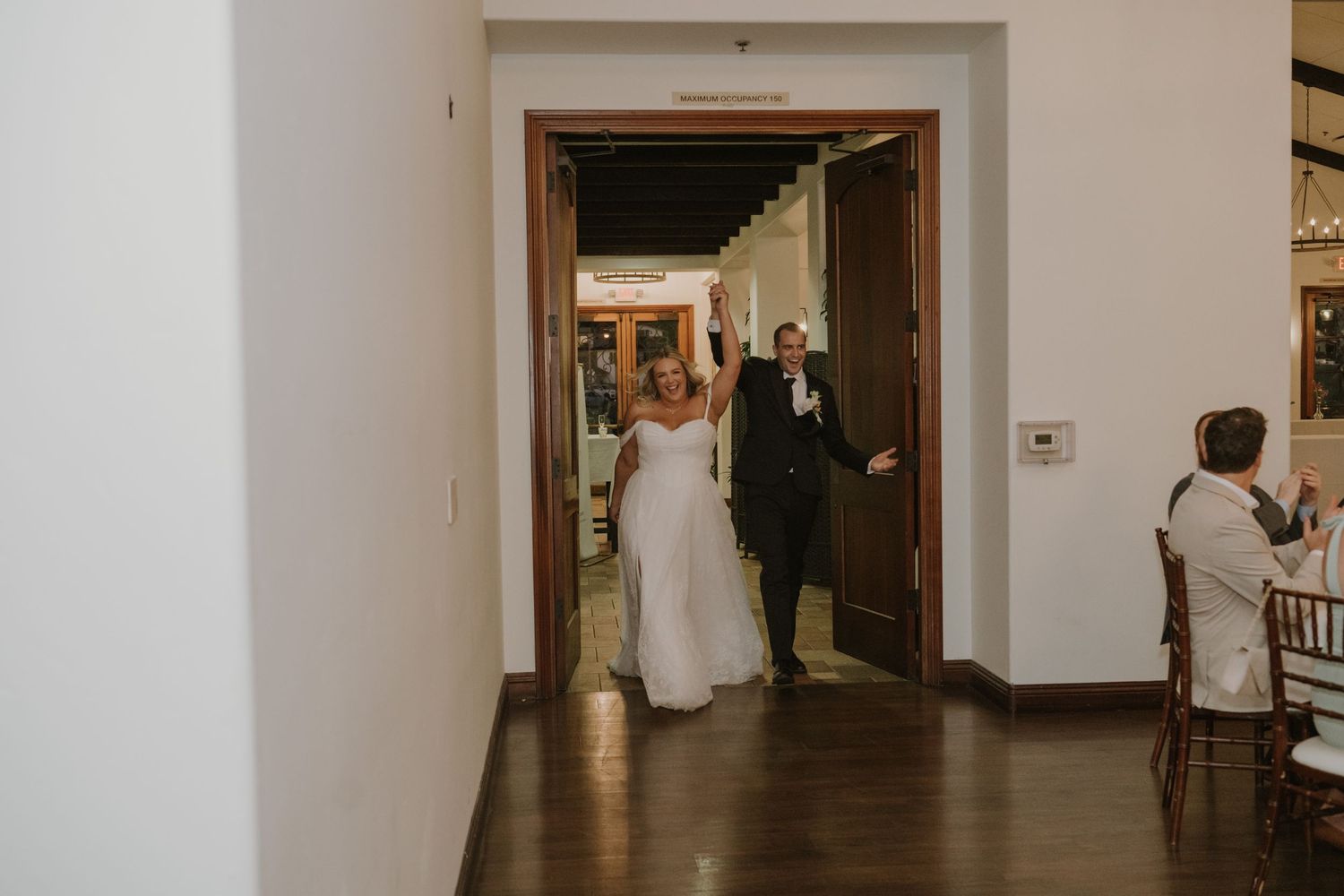Bride and groom making a grand entrance through double doors at their wedding reception.