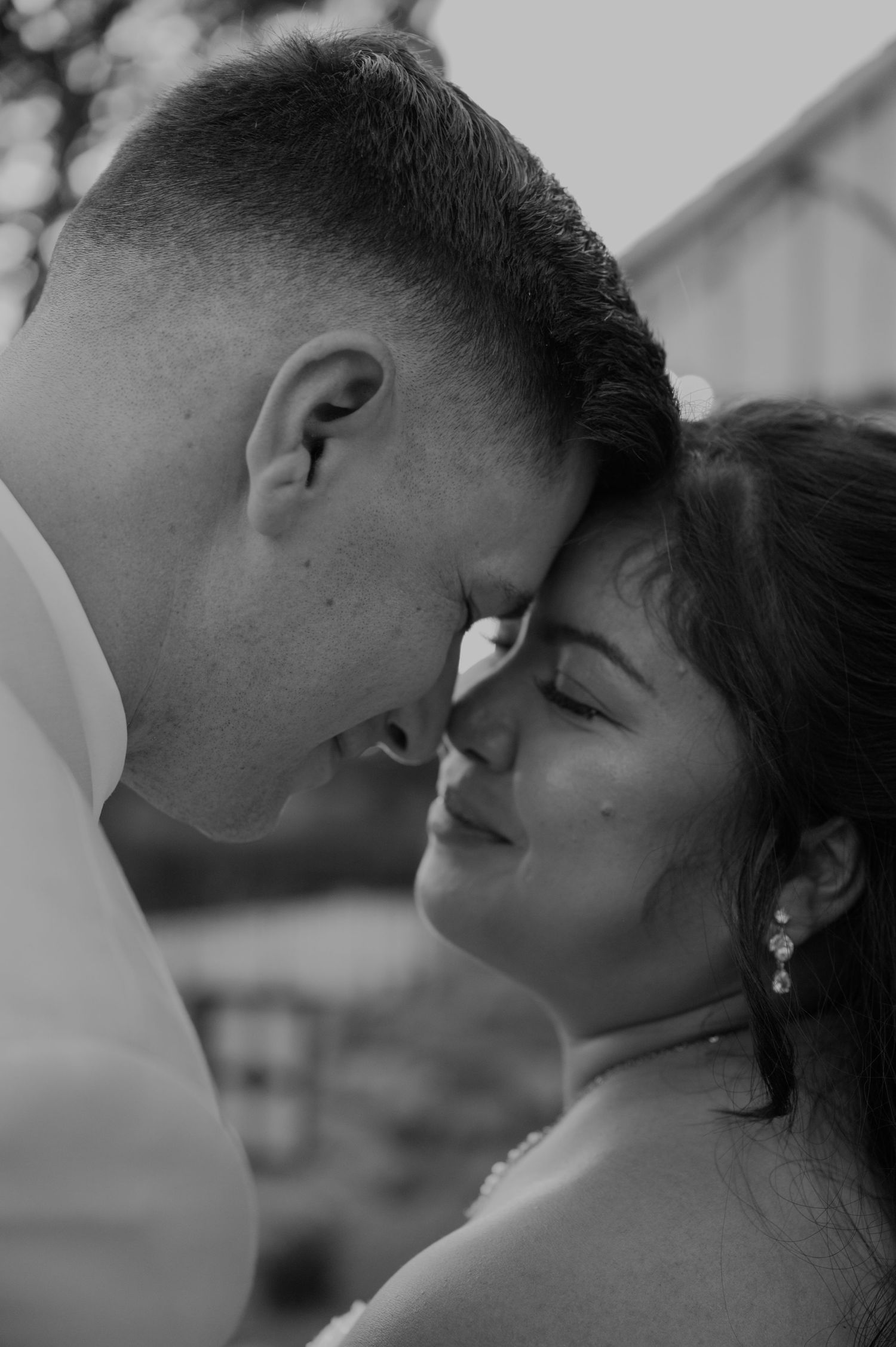 Bride and groom share intimate forehead touch moment in black and white.