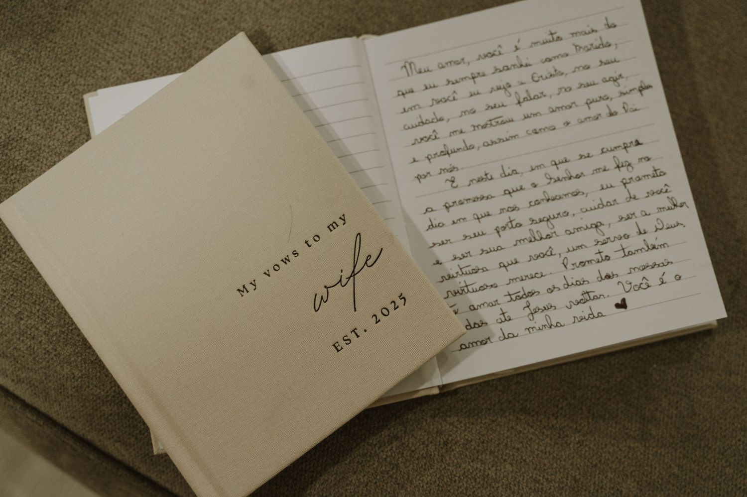 Open wedding vow book titled My Vows to my Wife Est. 2023 beside handwritten love letter on neutral background.