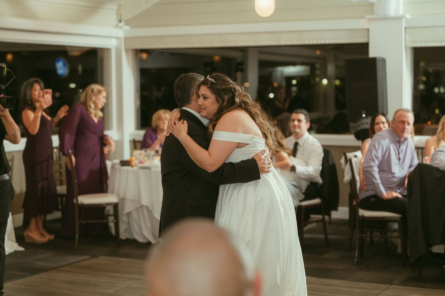 Newlyweds share an intimate embrace during their first dance as wedding guests watch and celebrate.