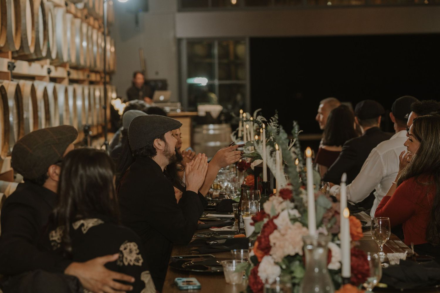 Dimly lit reception venue with tables decorated with candles and floral arrangements.