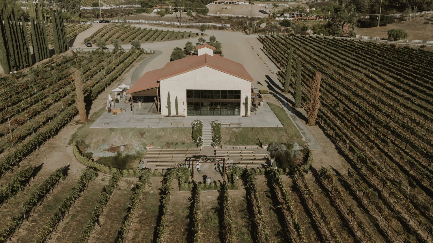 Aerial view of a winery estate with rows of grapevines and Mediterranean-style buildings nestled in the landscape.