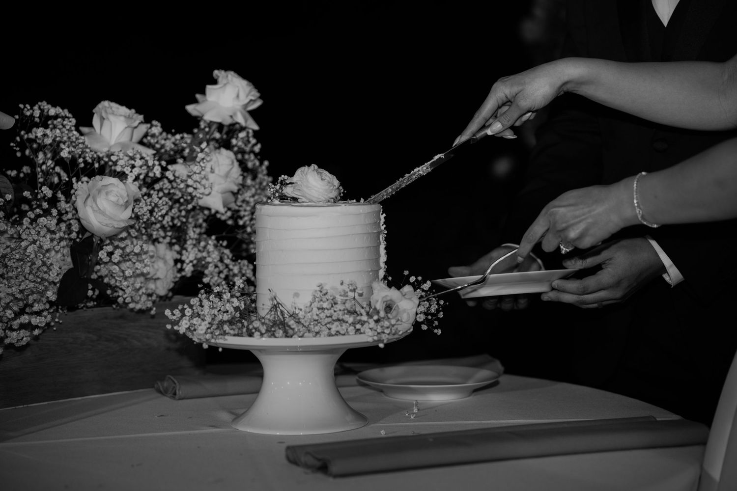 A white wedding cake being cut and served at an elegant reception.