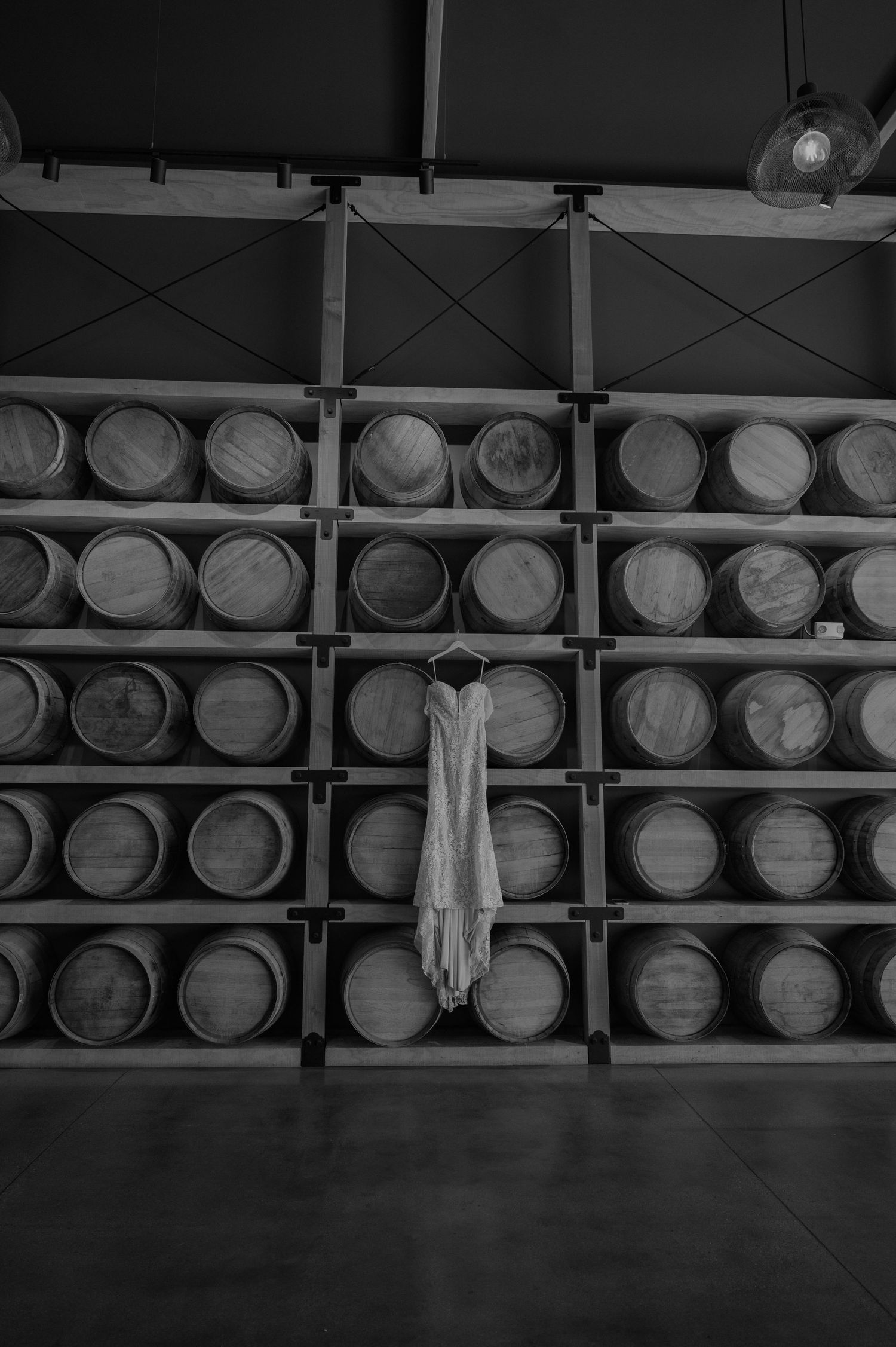 Black and white image of wooden wine barrels stacked in rows at a winery cellar.