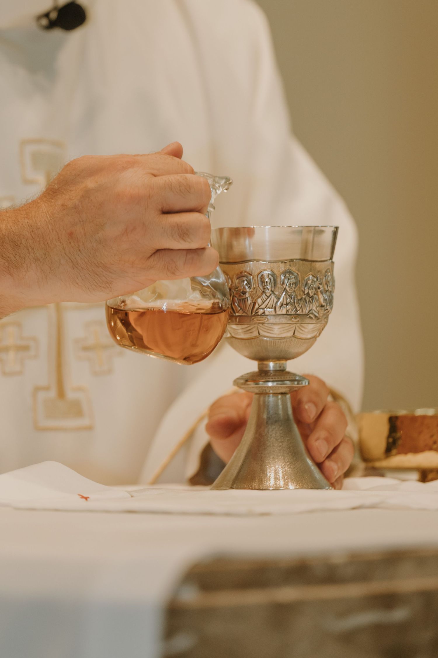 Catholic priest prepares Eucharist chalice with wine during wedding Mass ceremony.