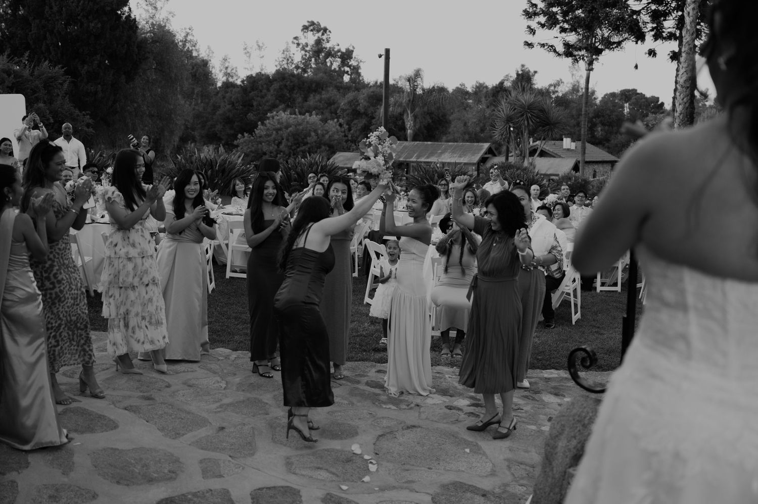 Guests dancing outdoors at a wedding reception in black and white photography.