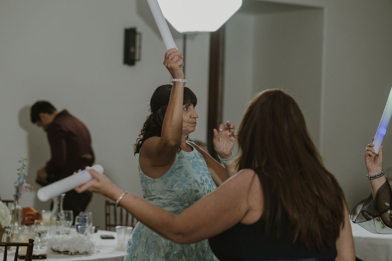 Wedding guests dancing and celebrating energetically at a lively indoor reception party.