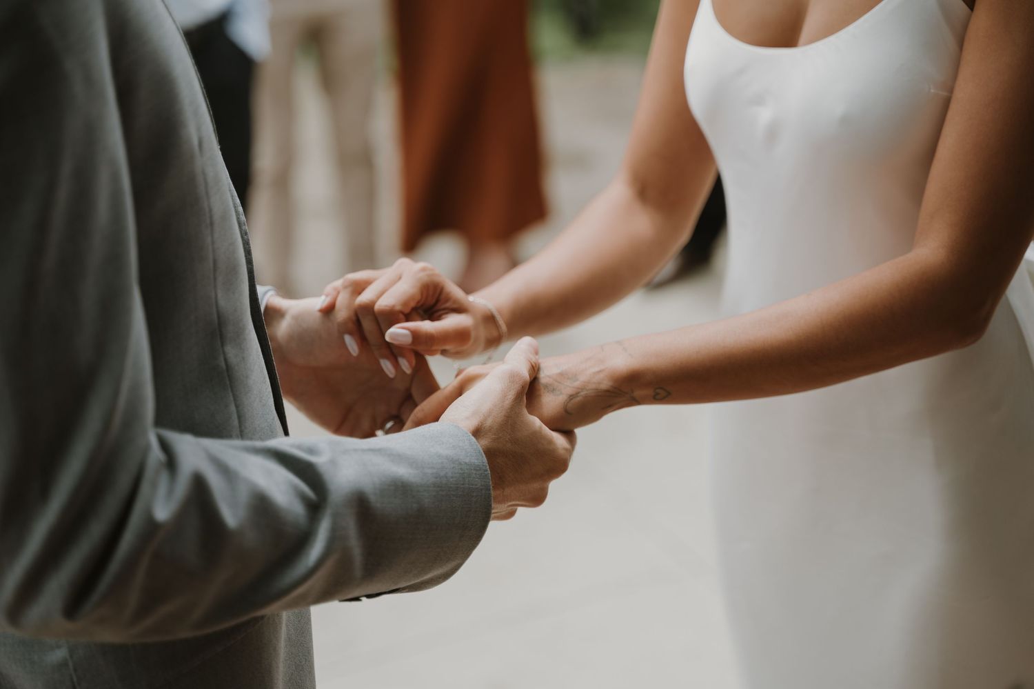 Close up of couple holding hands during wedding ceremony.