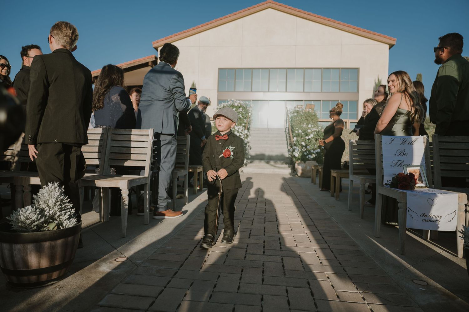 Outdoor wedding ceremony with guests seated along a stone pathway.
