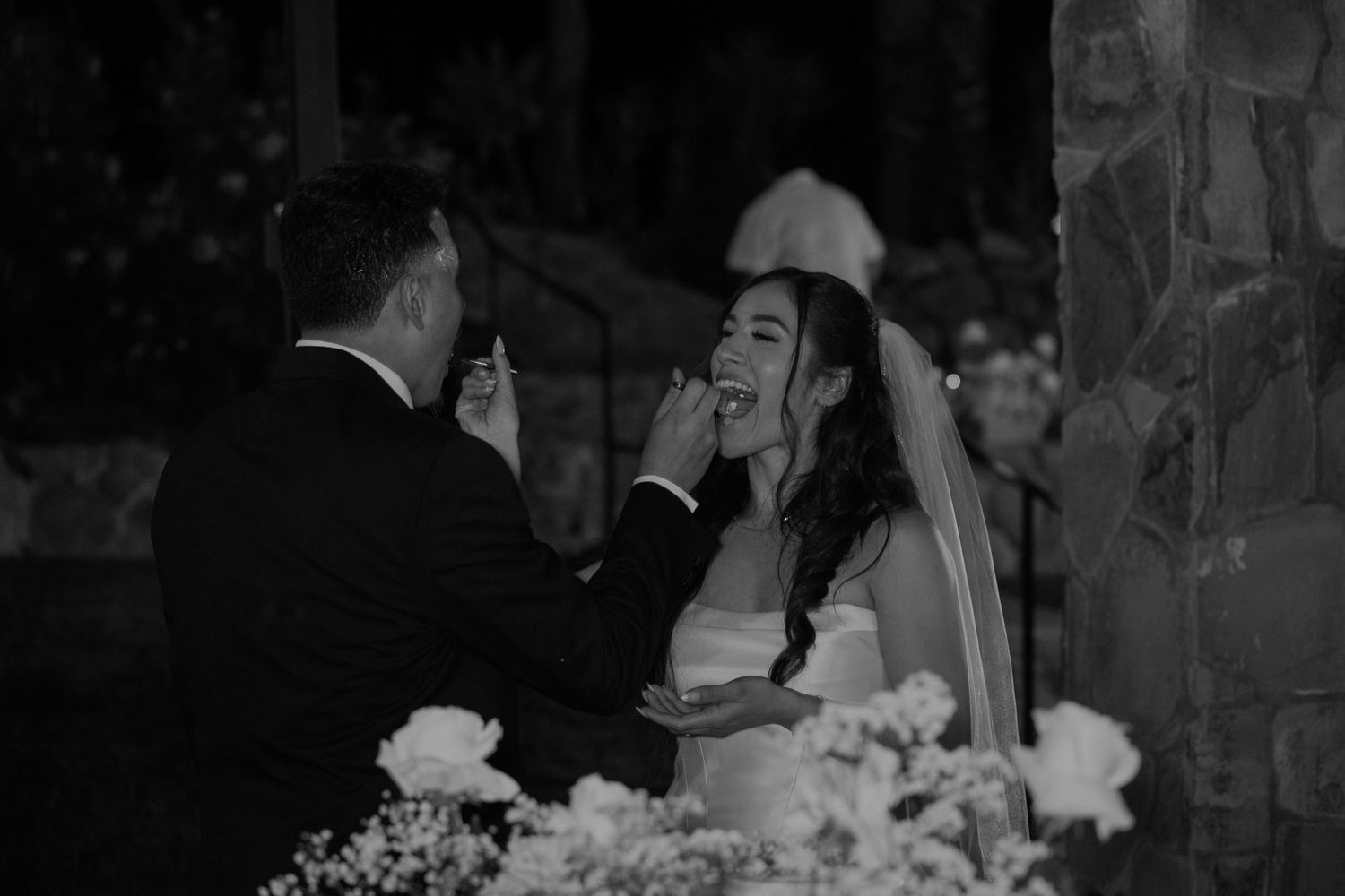 Guests dancing and celebrating at a nighttime wedding reception under string lights.