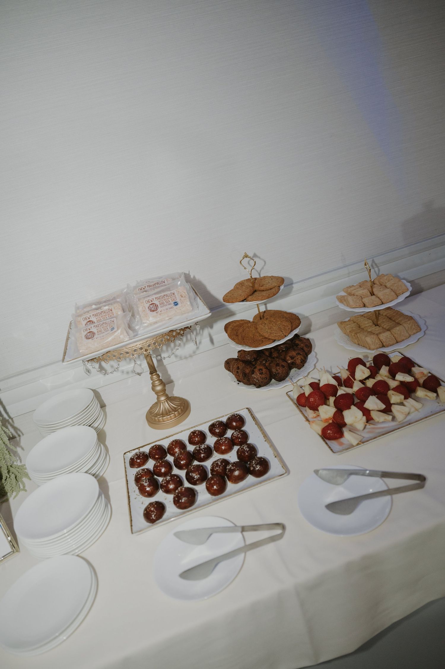 Dessert table with elegant cake stands displaying chocolate treats and sweets at a wedding reception.