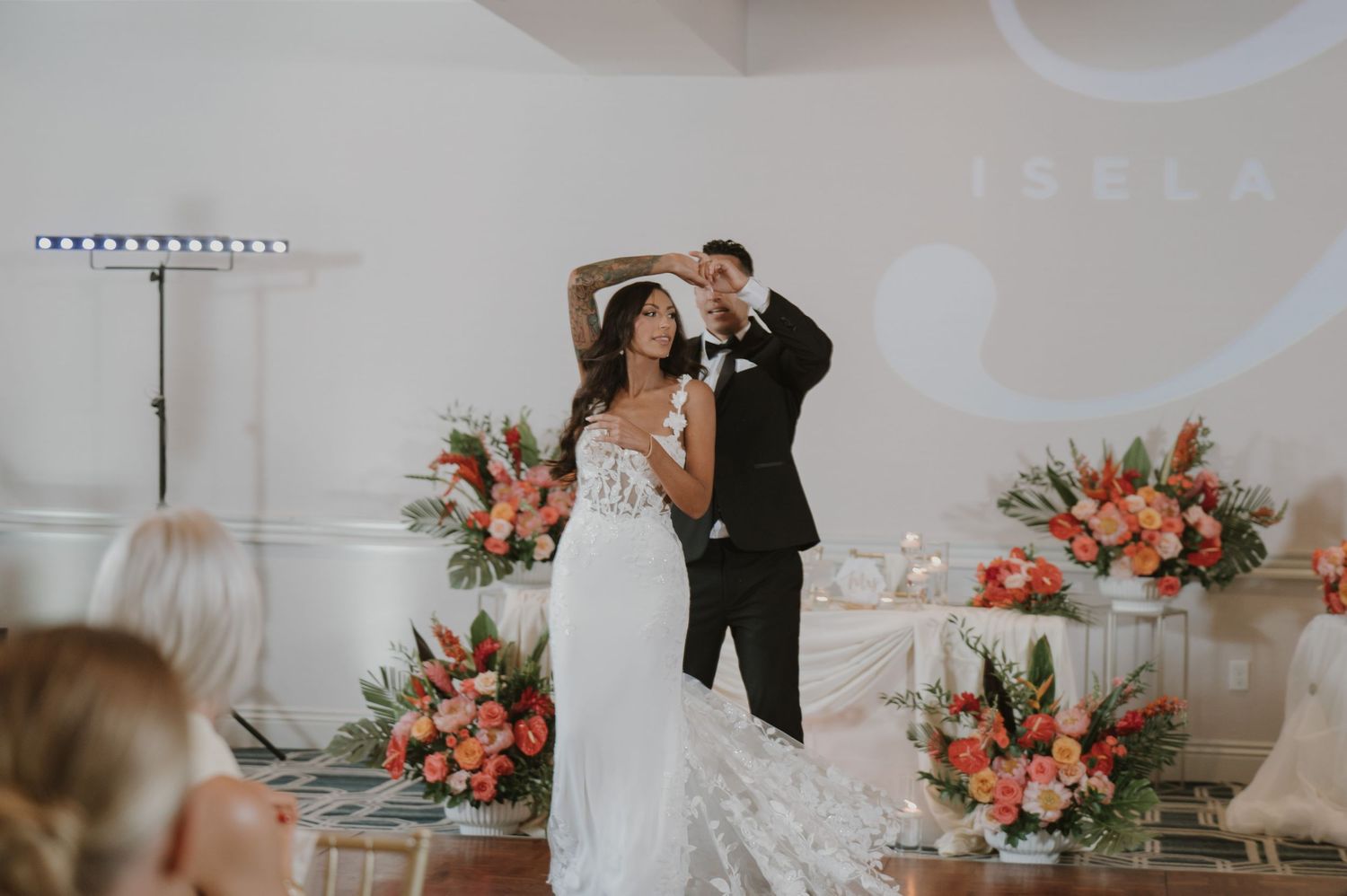 Elegant wedding reception setup with coral floral arrangements and white table settings in a modern venue.