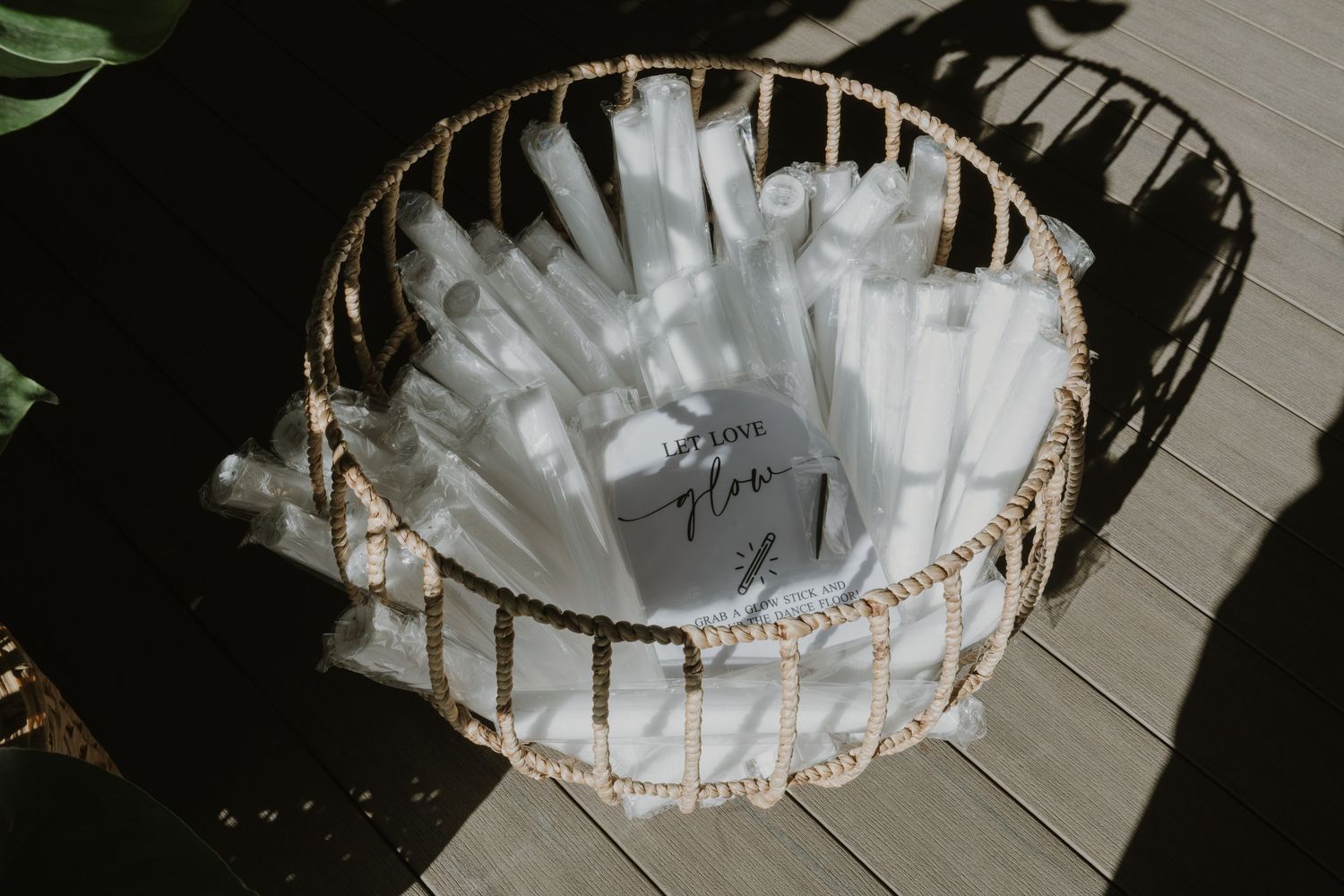 Wicker basket filled with rolled white programs and a handwritten sign on a wooden deck.