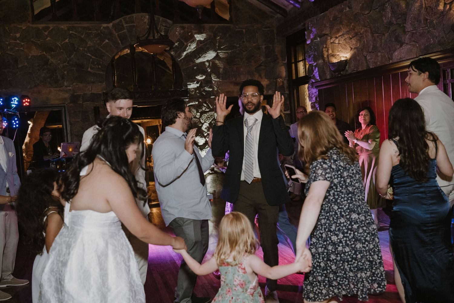 Bride and groom celebrating with guests on a lively wedding reception dance floor.