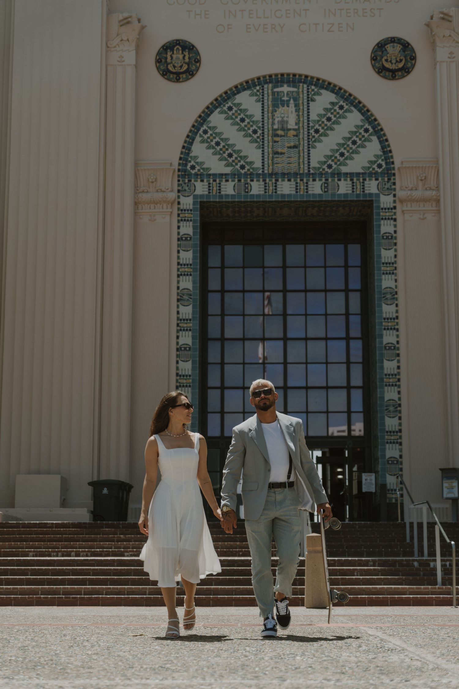 Couple posing in front of a grand building with classical architecture and columns.