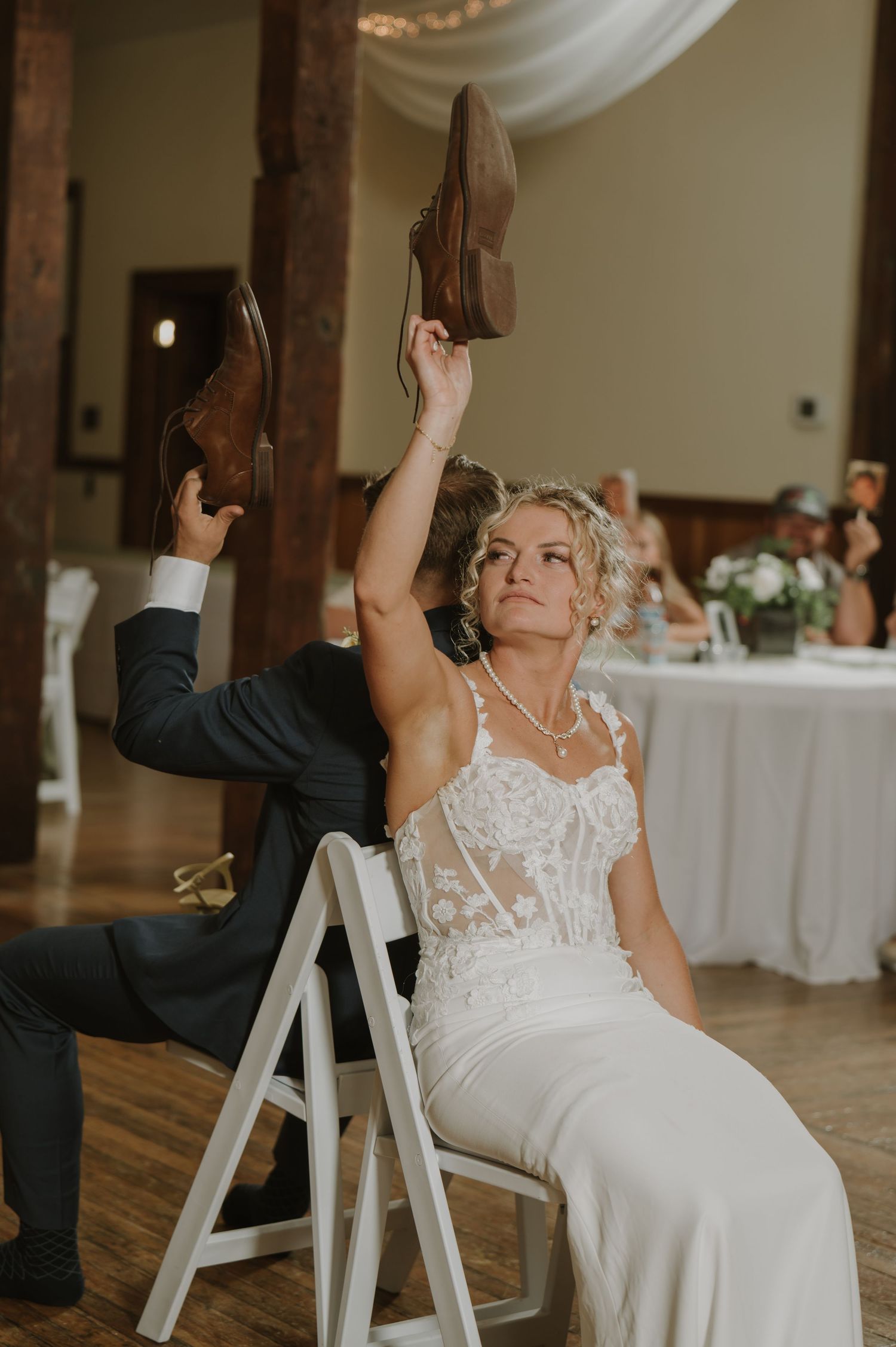 Wedding couple plays a fun reception game while seated in white chairs.