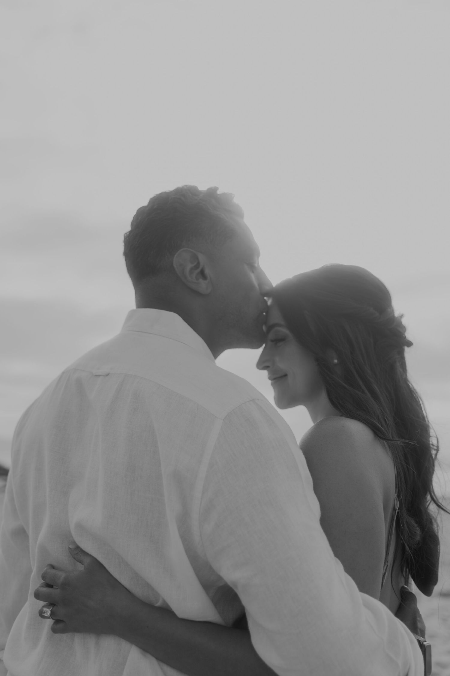 Romantic black and white beach portrait sequence showing tender moments between couple.