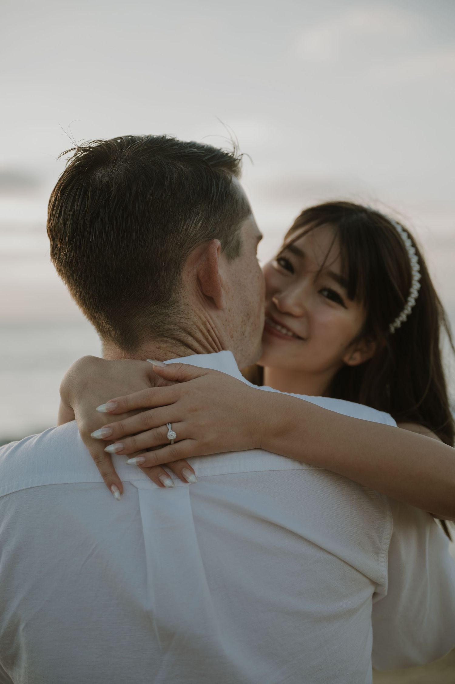 Intimate embrace captured against soft coastal lighting.