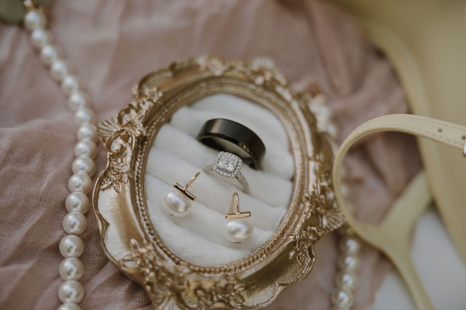 Vintage ornate frames and wedding details arranged on a soft surface.
