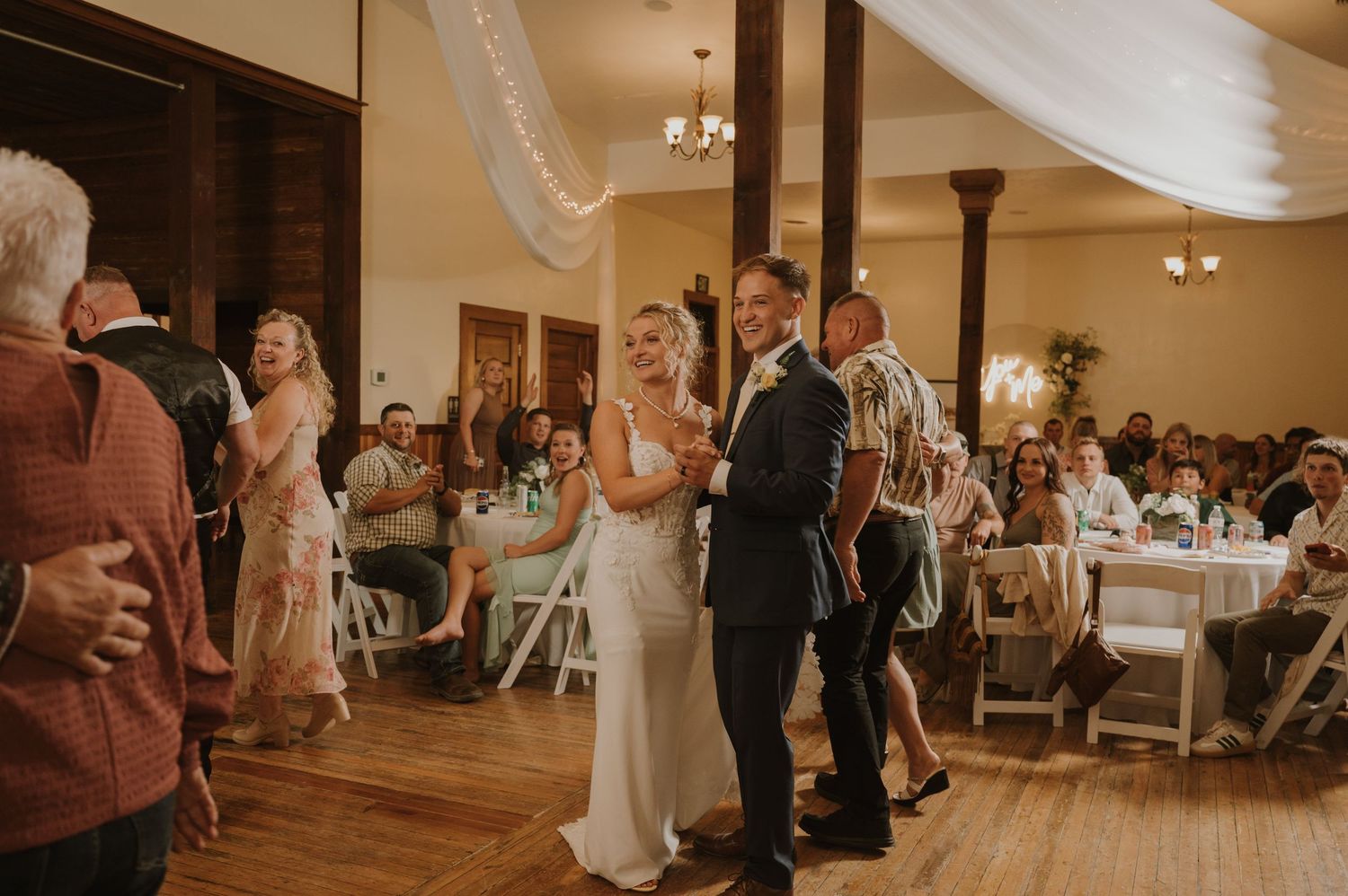 Guests enjoying themselves on a lively wedding reception dance floor with decorative lighting.