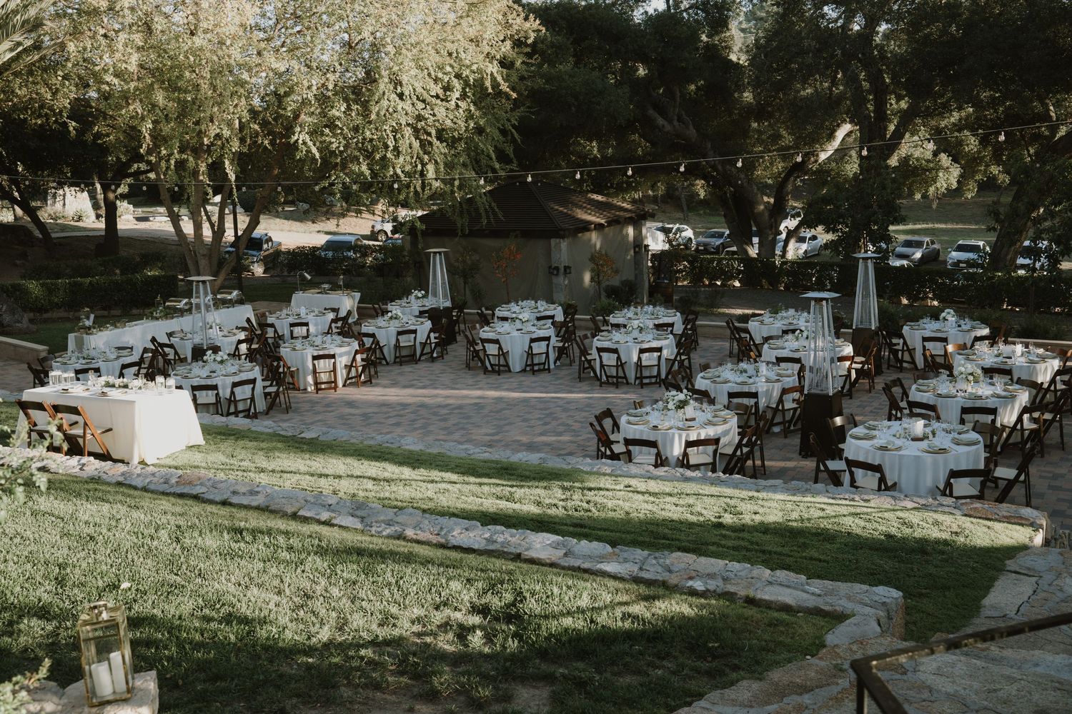 An outdoor wedding reception setup with white chairs and tables at dusk.
