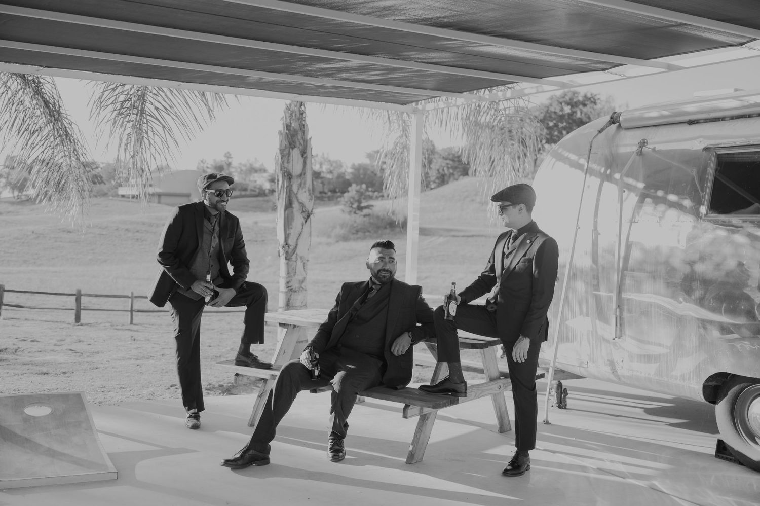 Panoramic sequence of figures sitting on benches in a monochrome setting.
