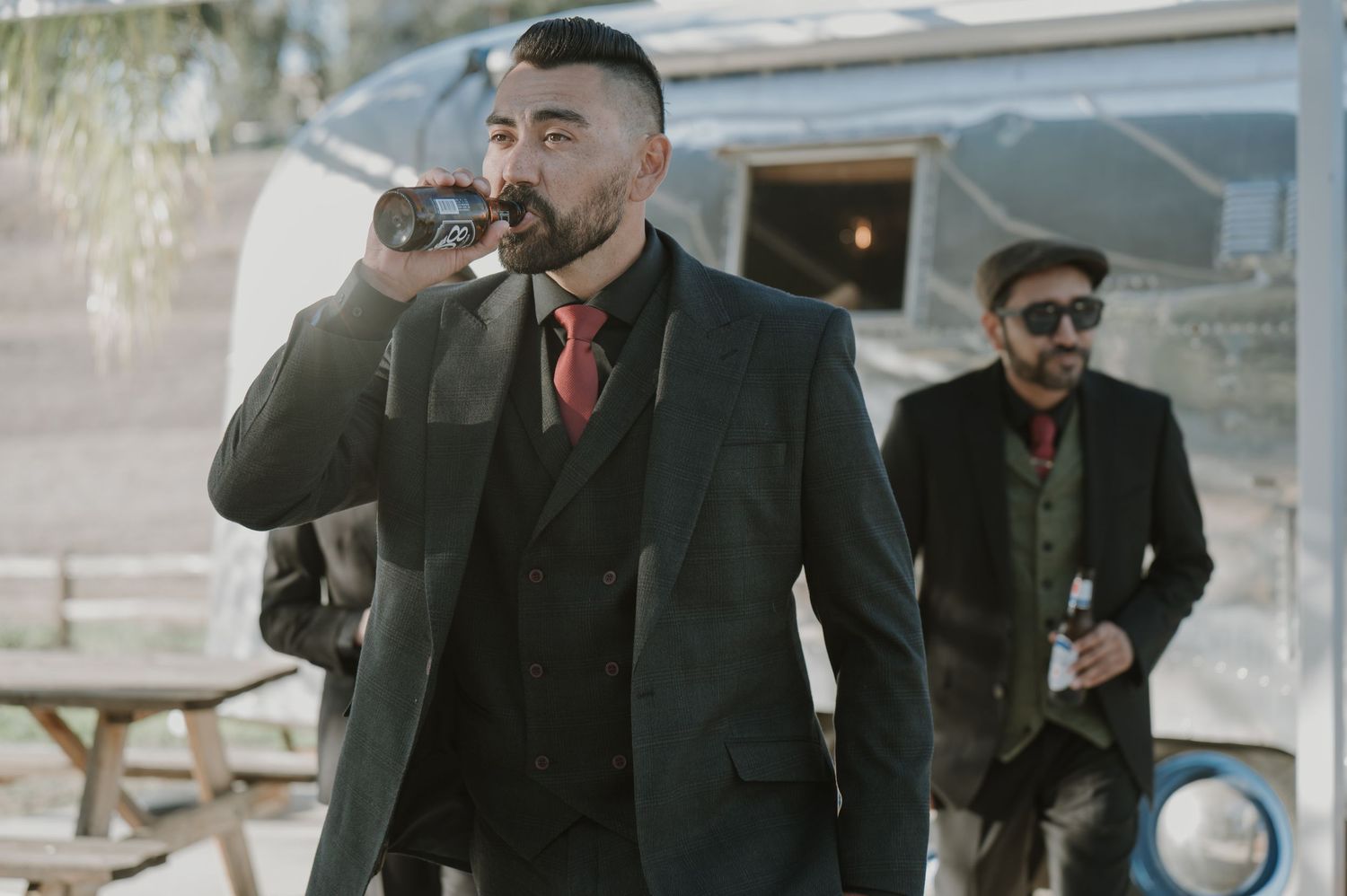 Man in dark suit speaking into microphone at outdoor event.