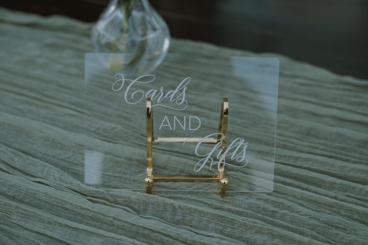Clear acrylic Cards and Gifts sign displayed on a gold easel stand at an elegant wedding reception table.