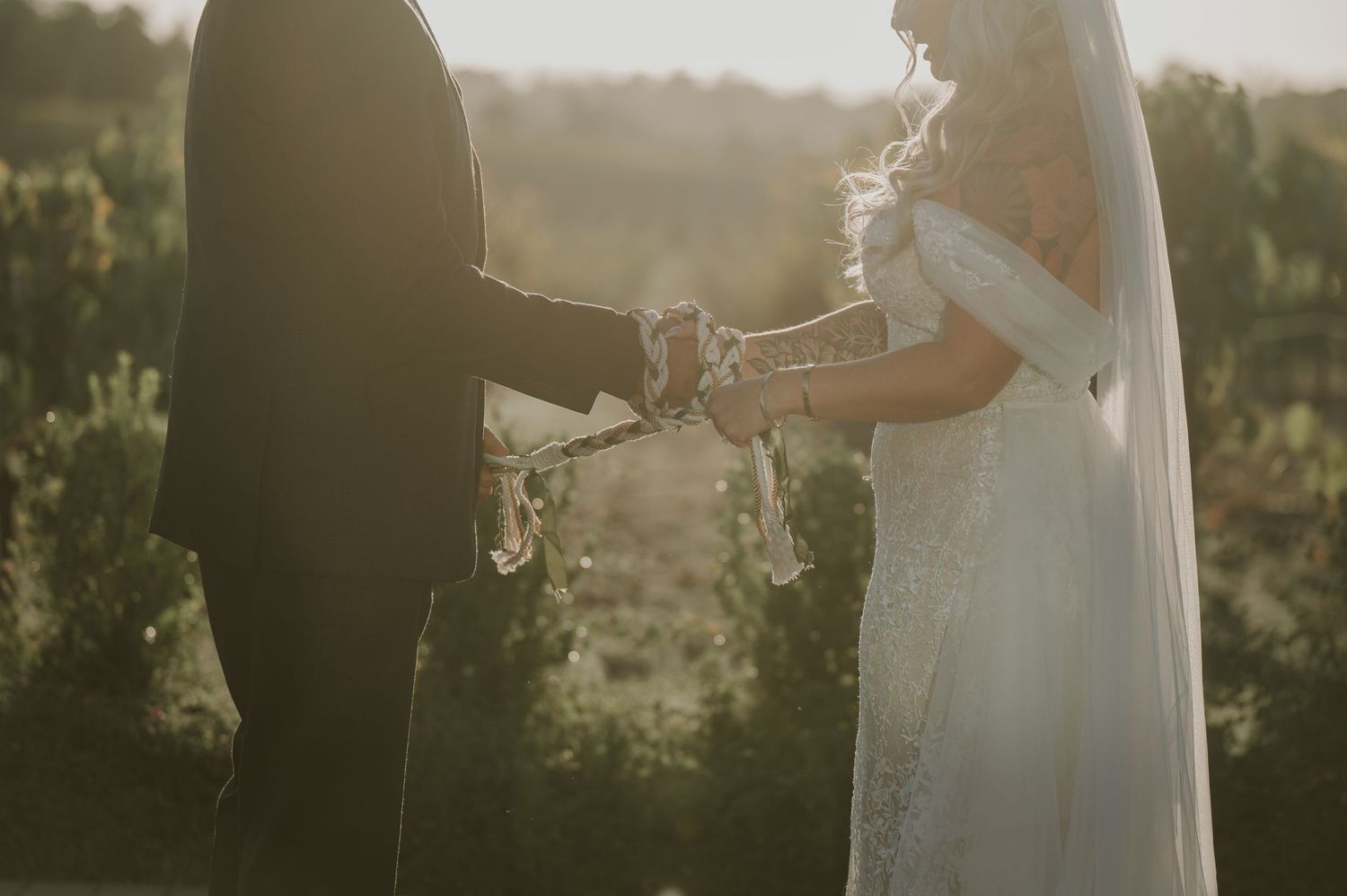Romantic sunset moment between newlyweds holding hands in a vineyard.
