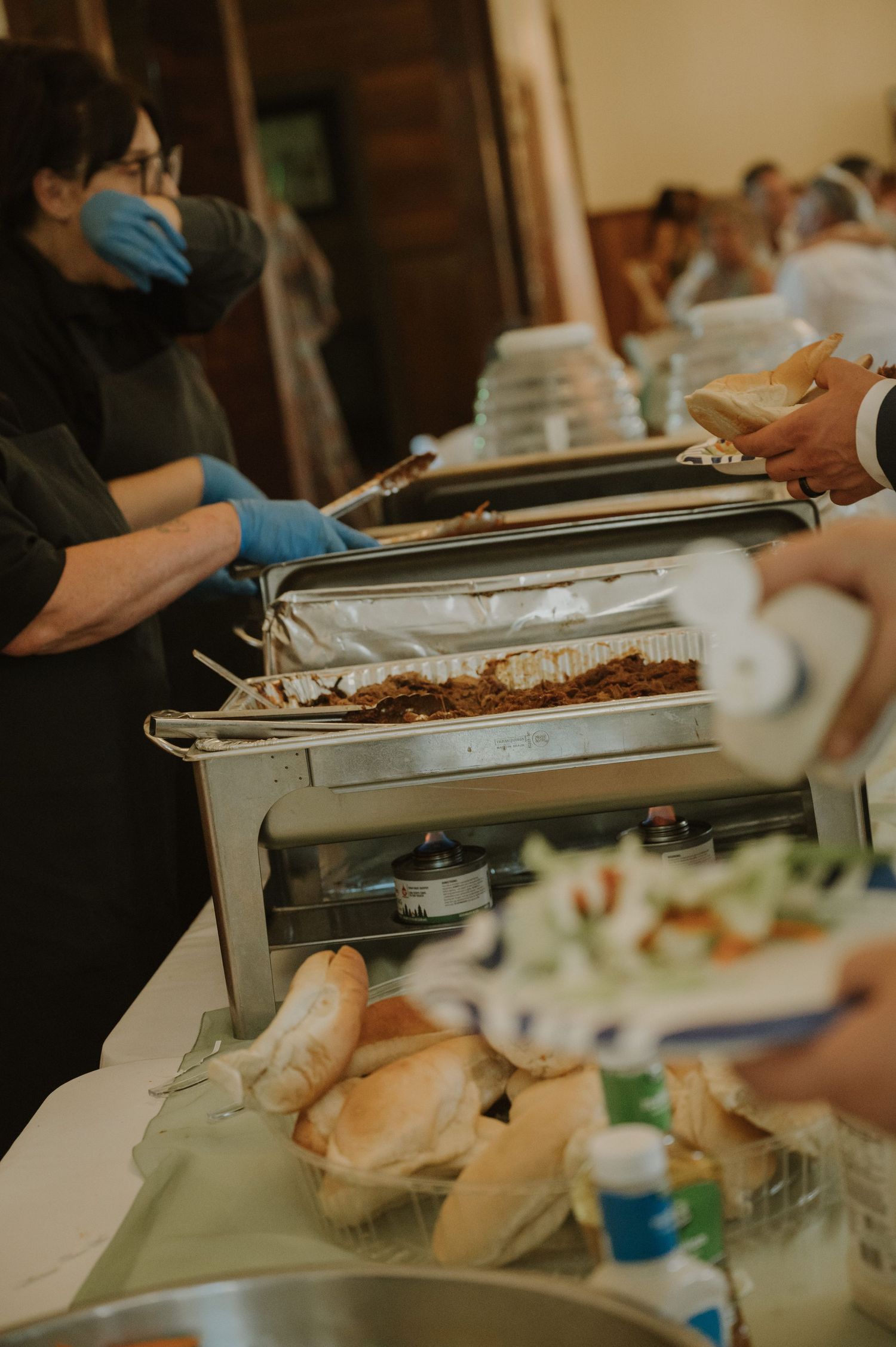 Wedding reception buffet setup with chafing dishes and serving utensils.