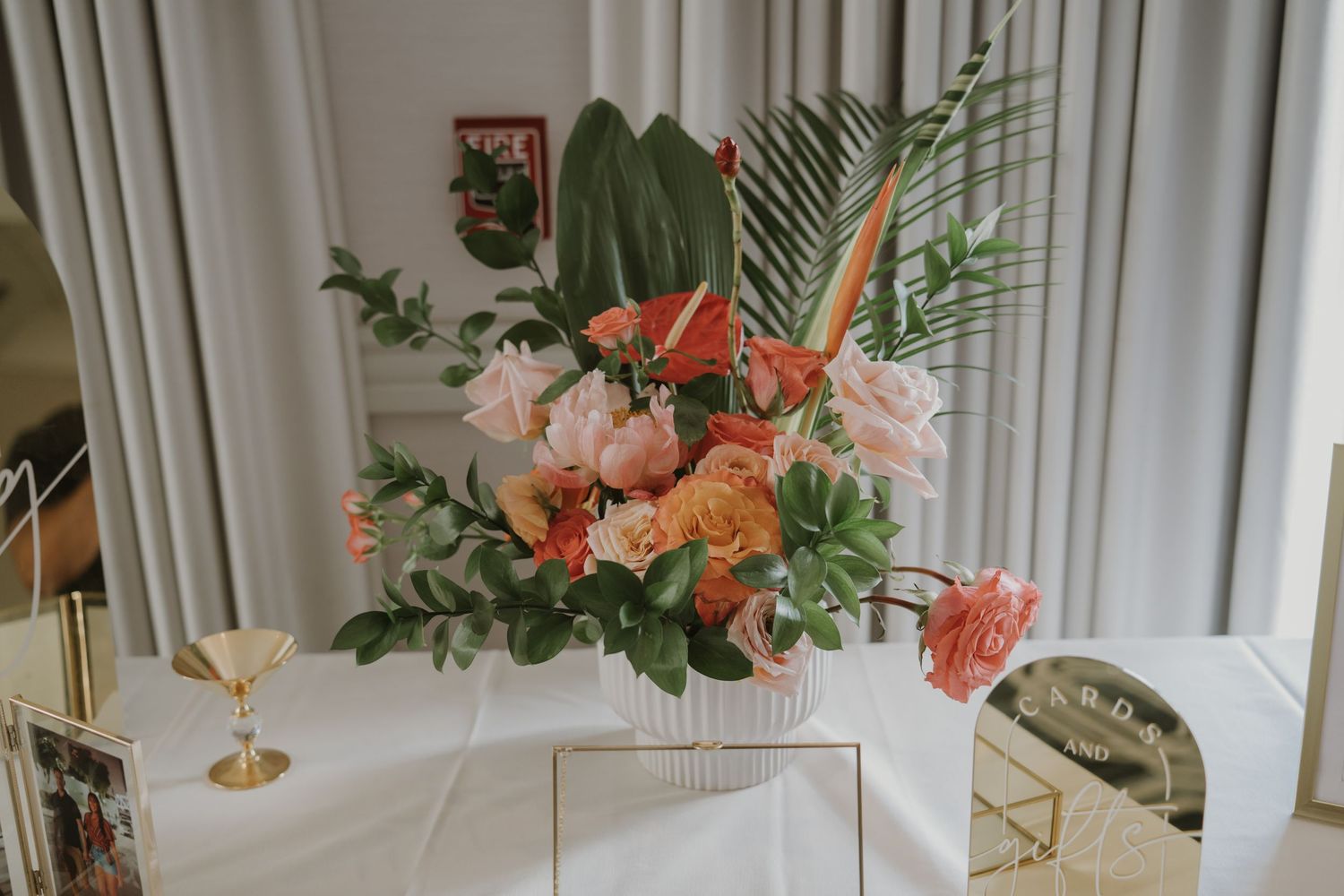 Modern wedding reception space with tropical floral arrangements and white draping.