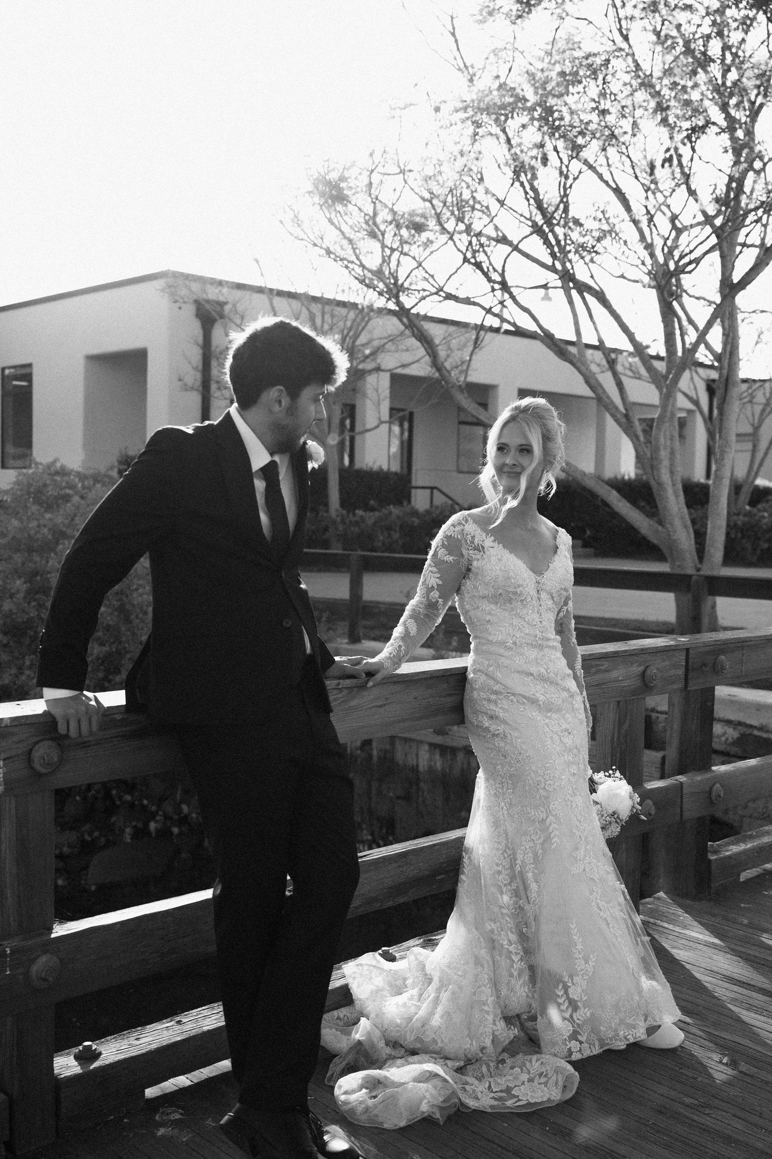 Black and white photo of bride and groom sharing a moment on a wooden deck.