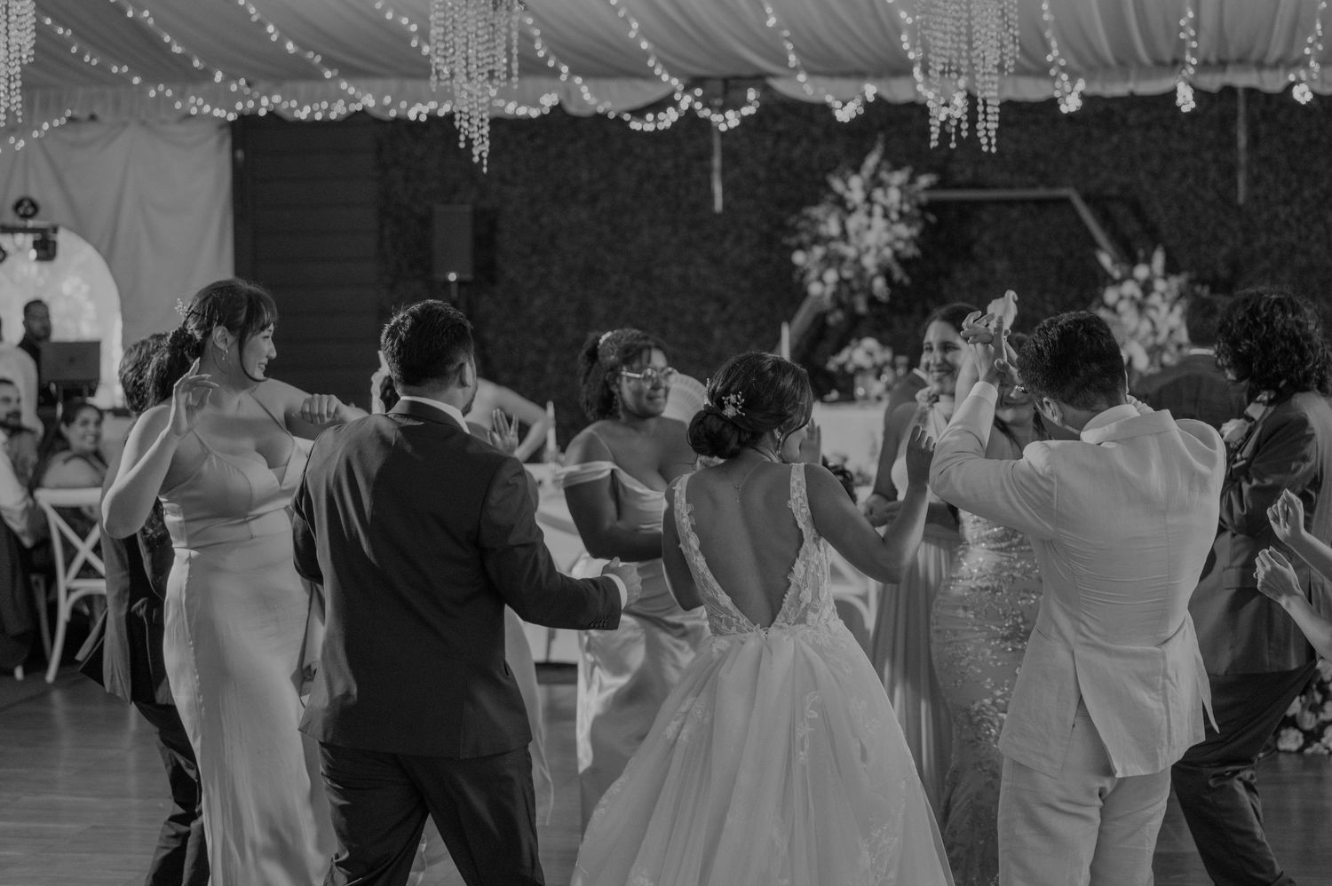 Black and white photo of bride and wedding party dancing together on the reception dance floor.