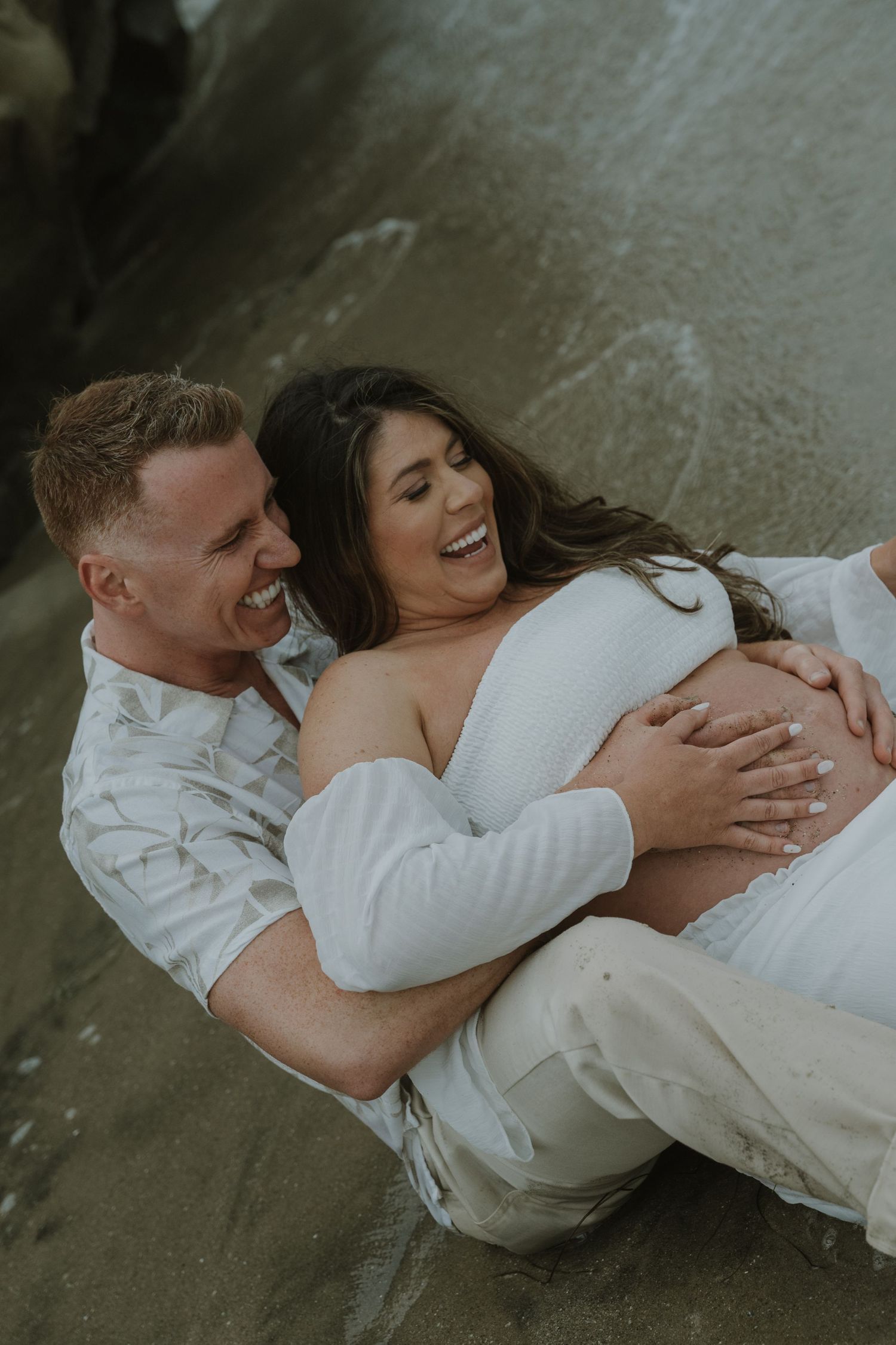 Intimate maternity portraits showing loving embrace on beach setting.