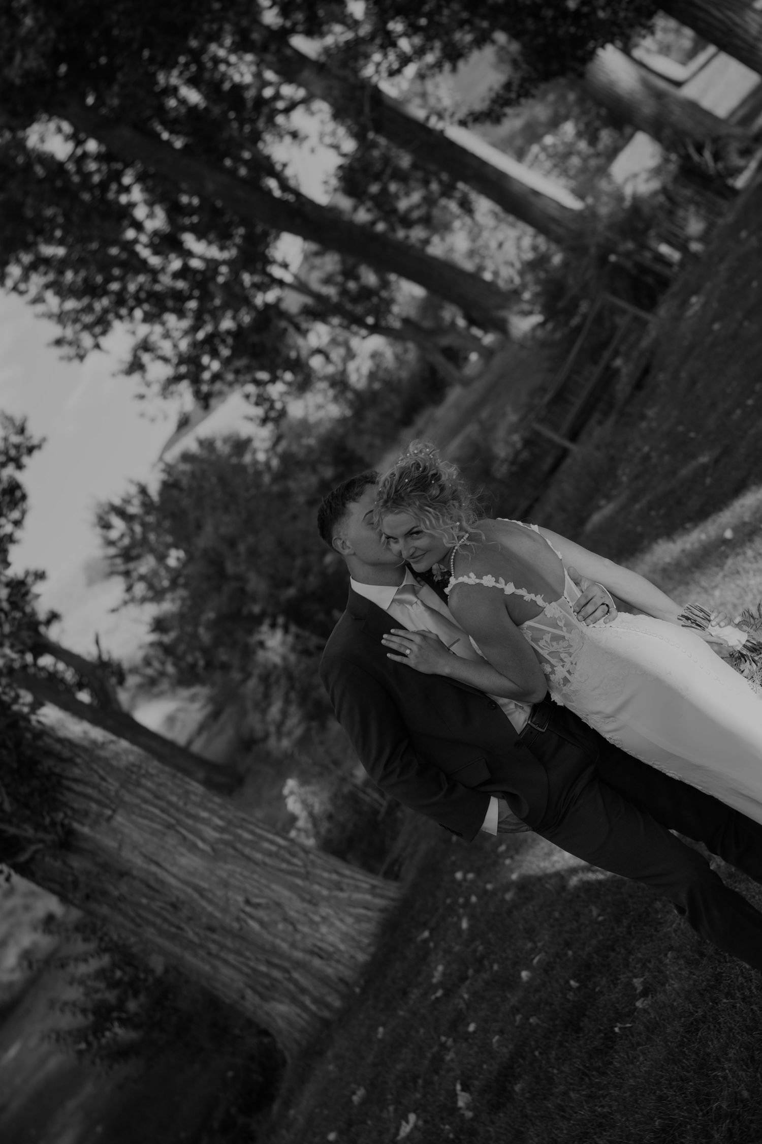 An artistic black and white wedding photo capturing shadows and light through trees.