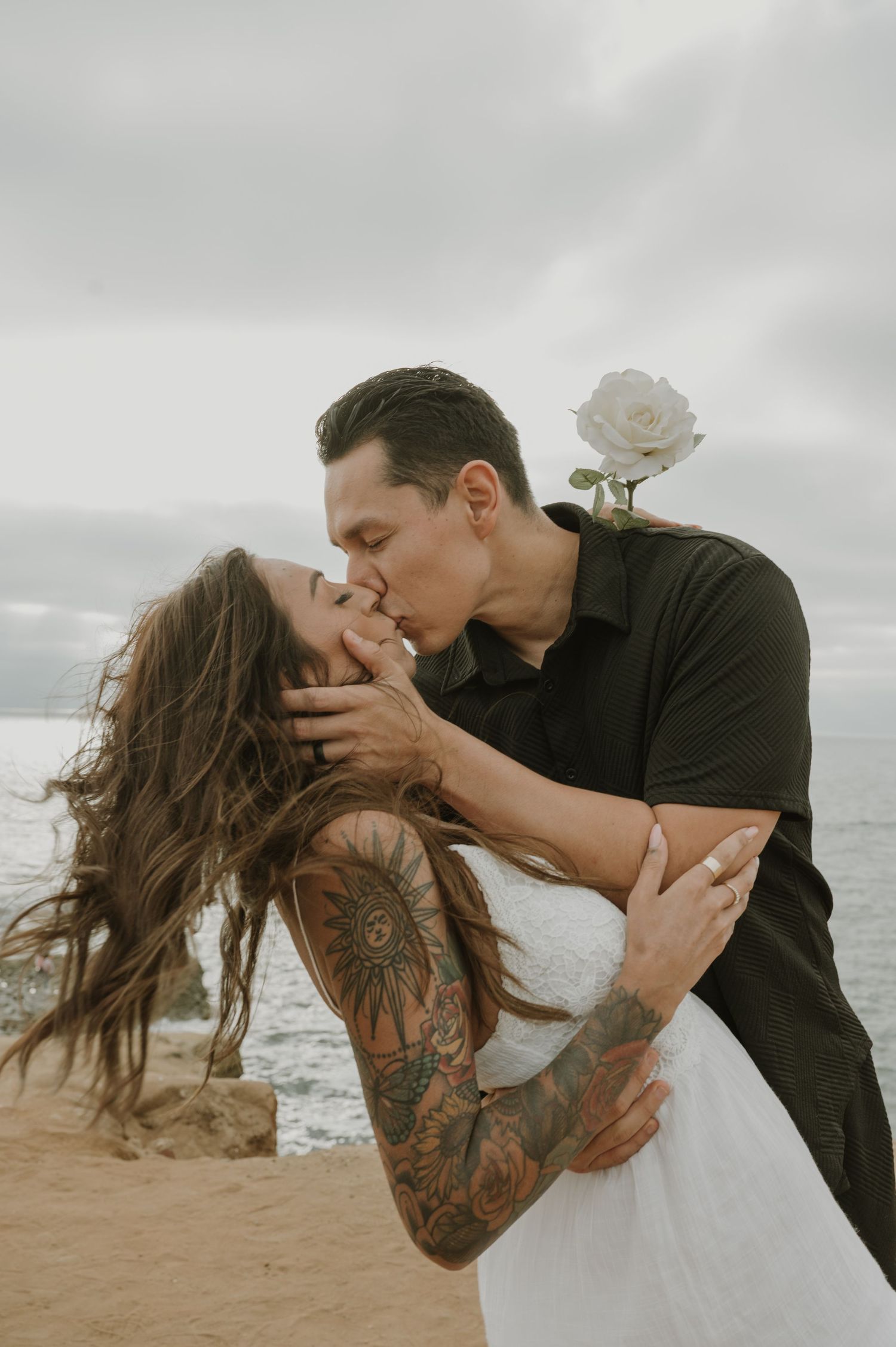 Passionate beach photoshoot sequence with wind-blown hair against cloudy coastal backdrop.