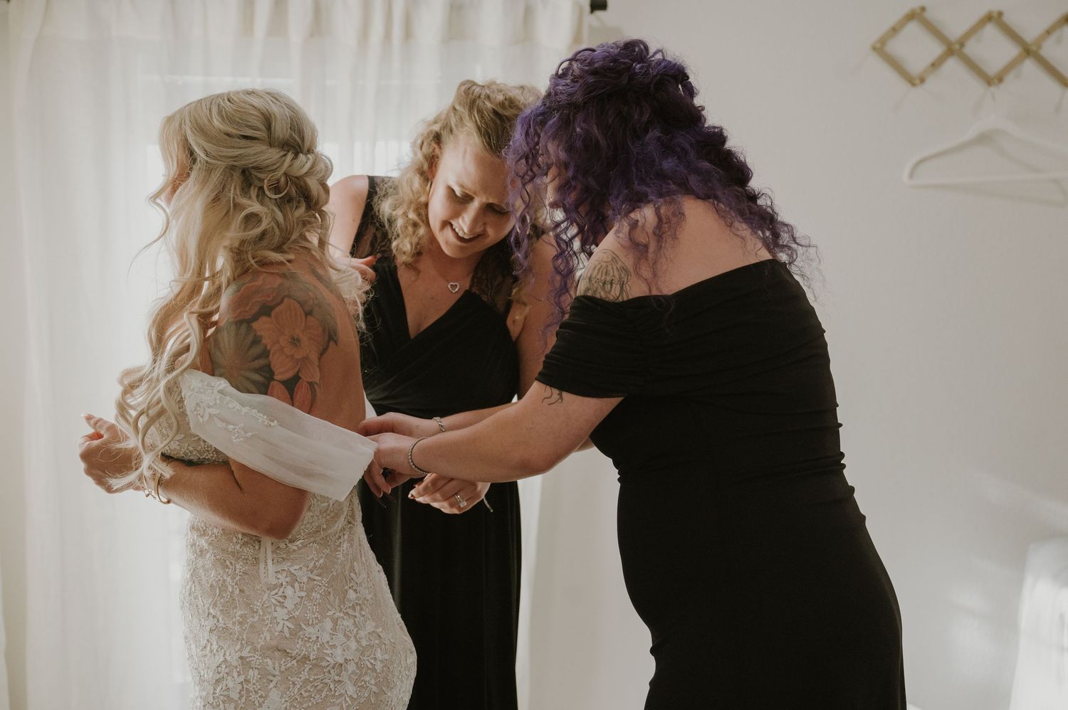 Wedding preparation scene with attendants helping adjust the bridal gown.