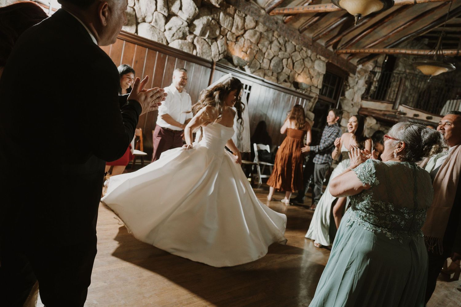 Wedding party dances in a rustic stone venue decorated with soft lighting.