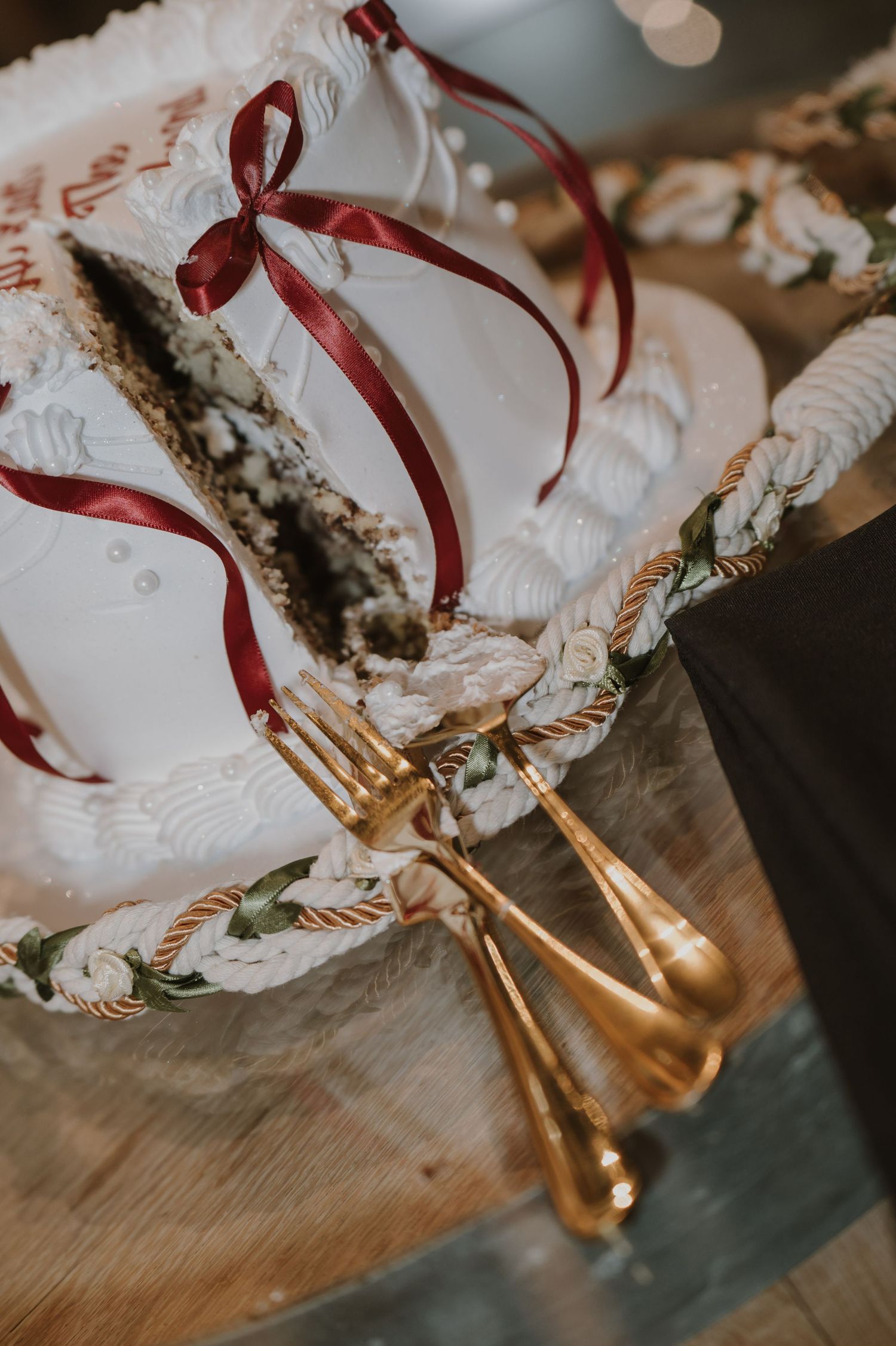 White decorative bags with red ribbons and gold utensils arranged on wooden surfaces.