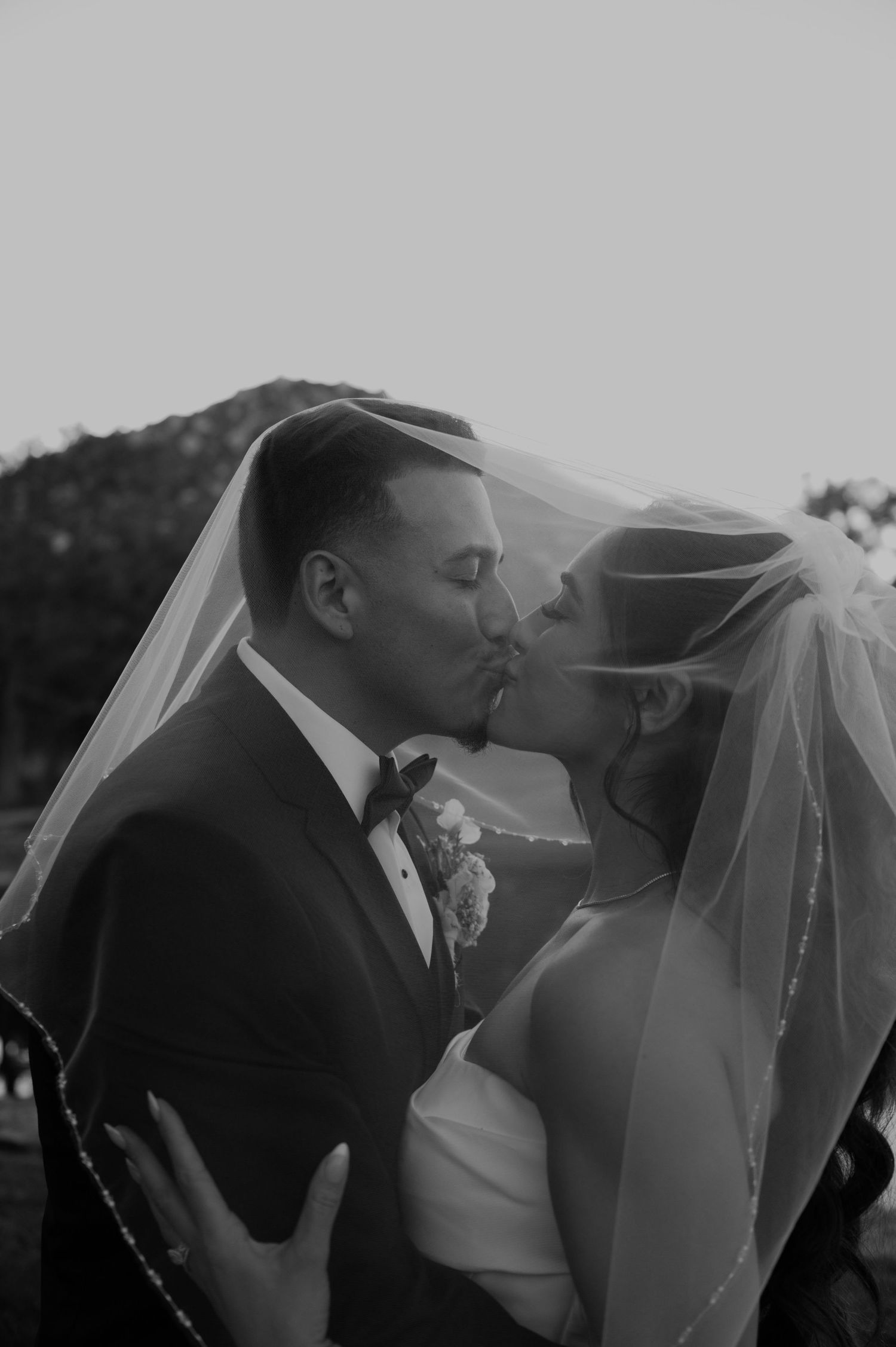 Intimate black and white portrait of couple sharing tender moment under bridal veil.