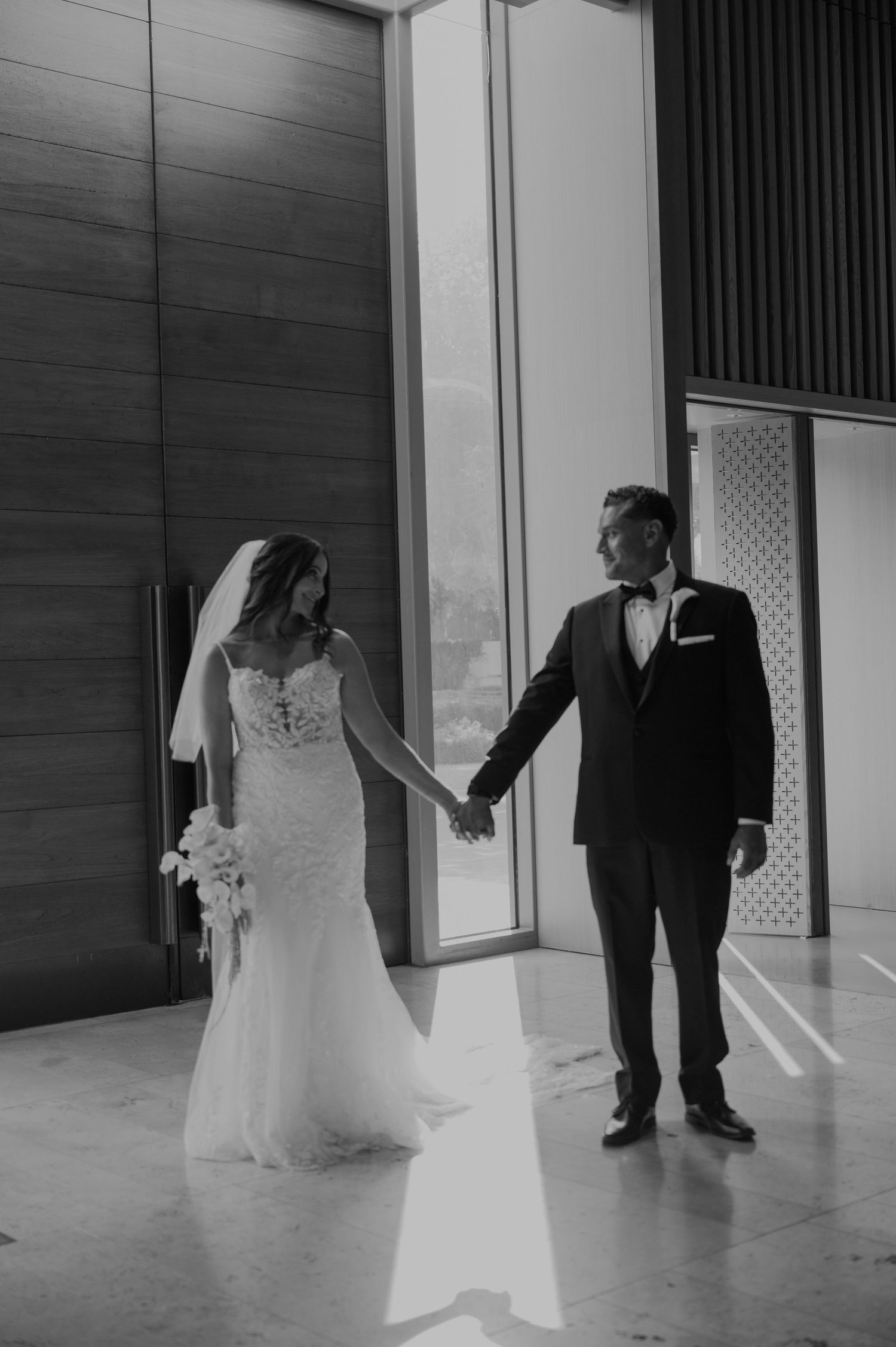 A series of black and white wedding photos showing a couple's first look in an elegant indoor venue.