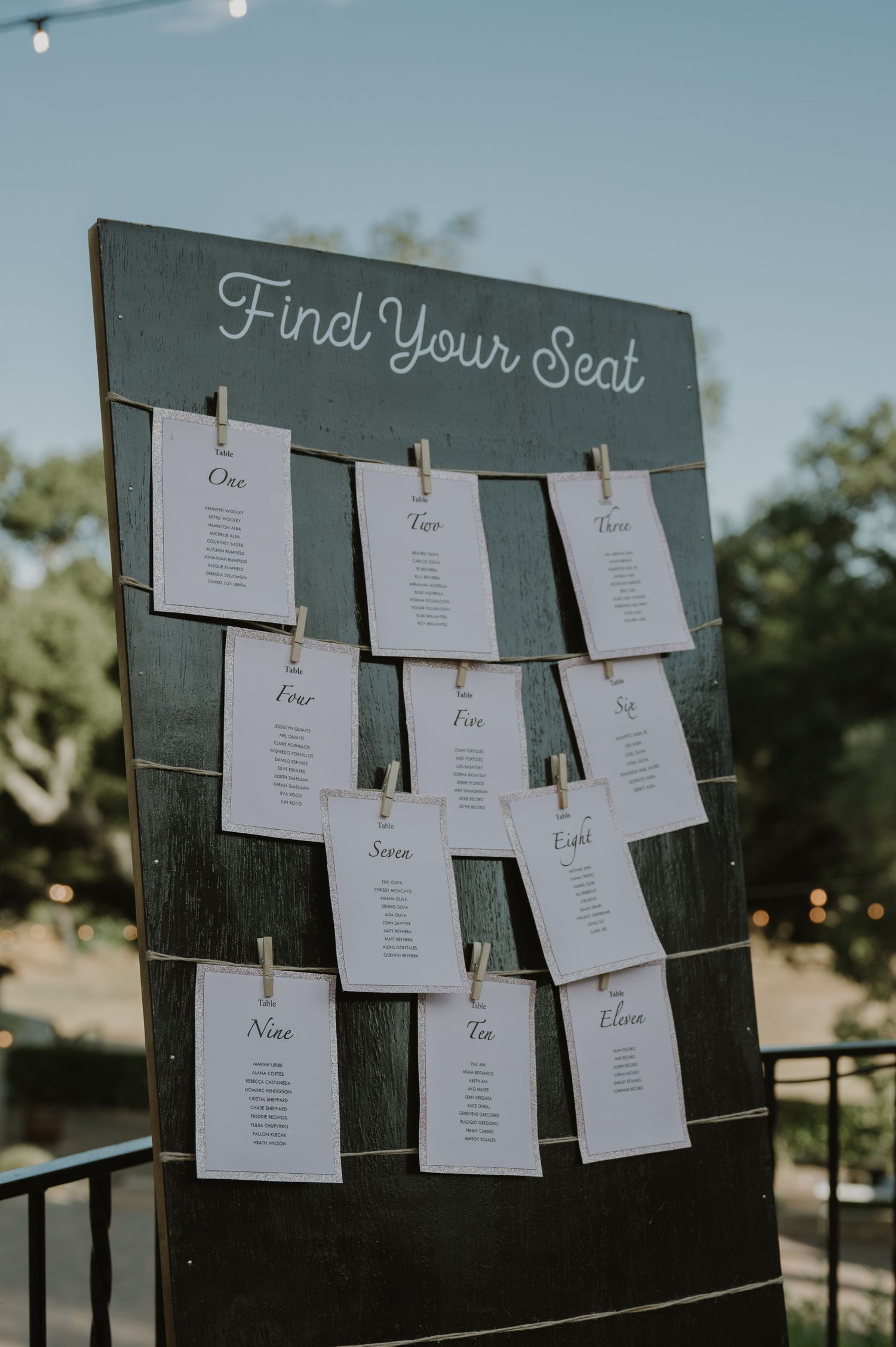 Rustic wooden wedding seating chart board with cards clipped by clothespins labeled Find Your Seat.