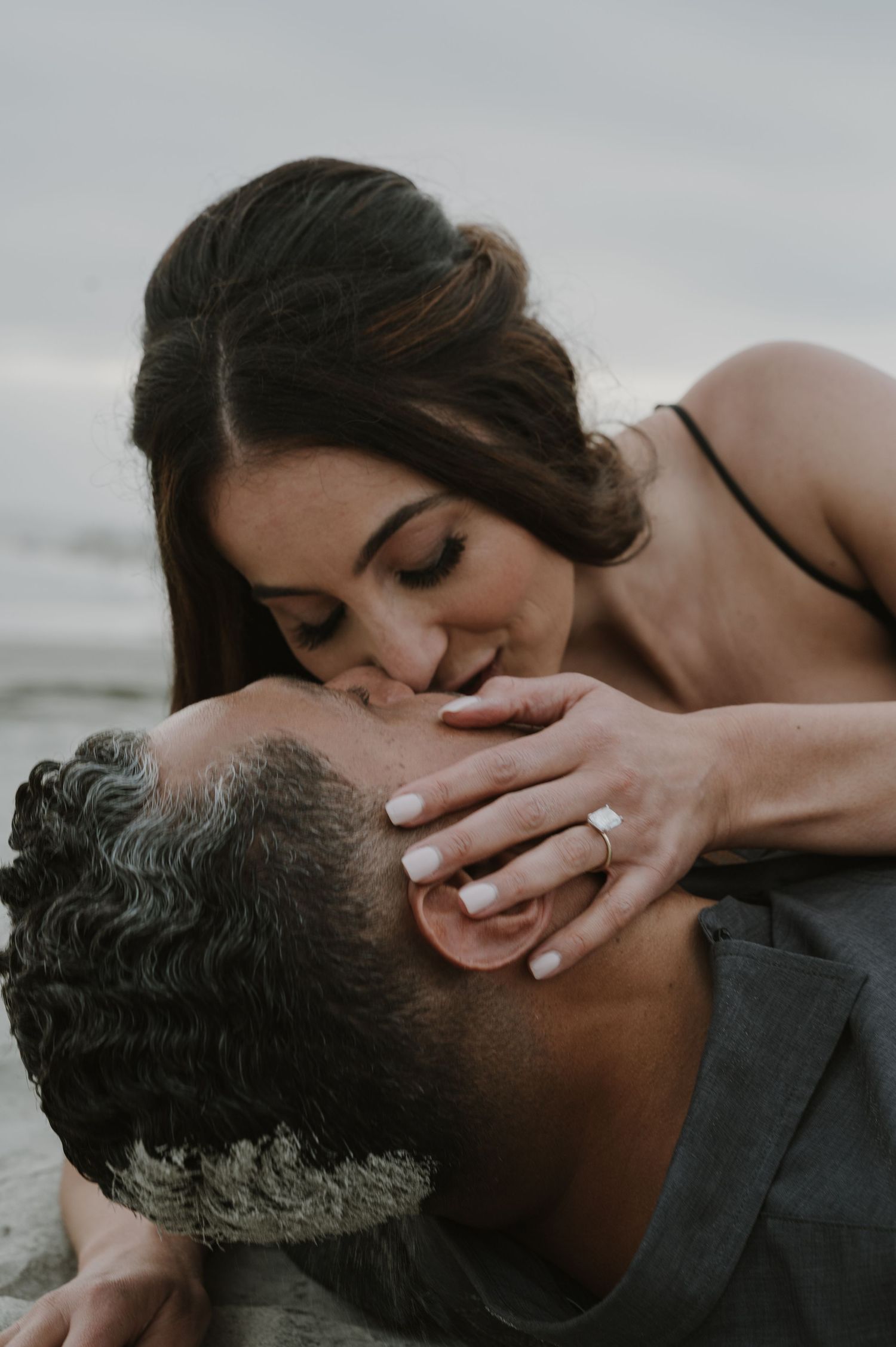 Close-up romantic moment captured in moody lighting by the ocean.