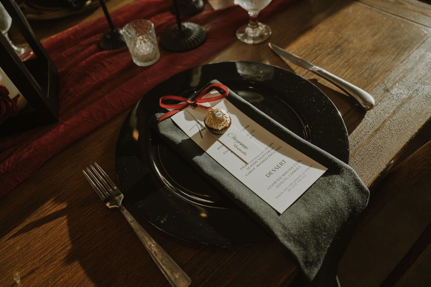 Place settings and menus on dark wooden tables with moody lighting in a winery setting.