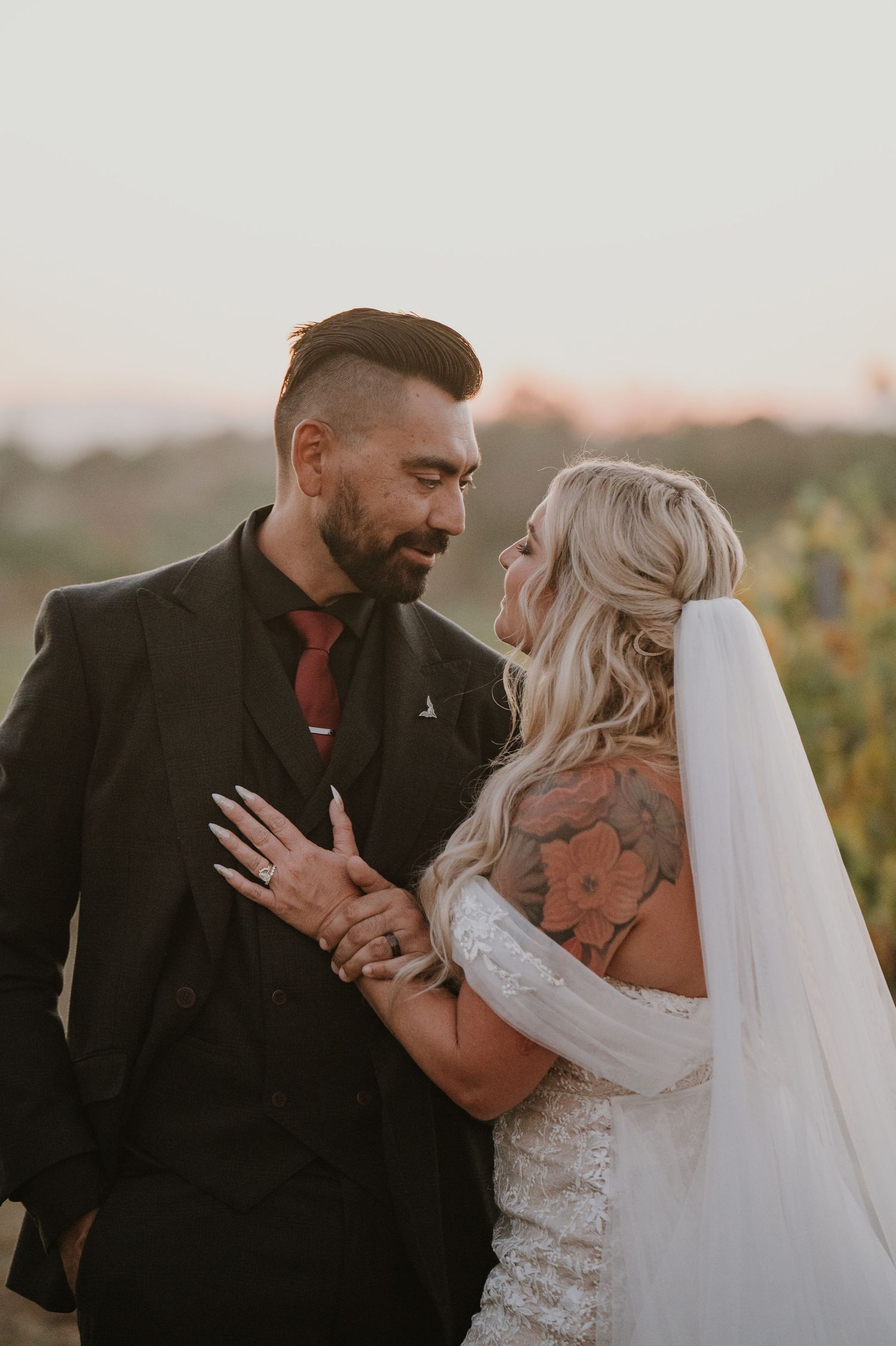 Intimate sunset portrait of couple embracing in vineyard setting.