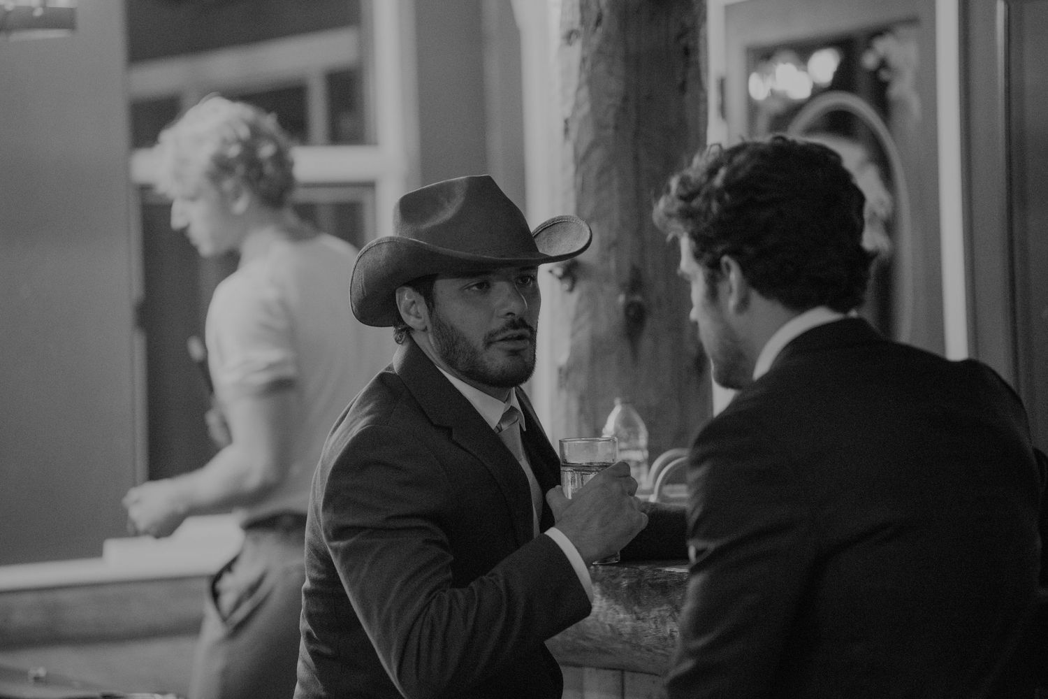 Black and white photo of two men in suits having conversation at elegant wedding reception.