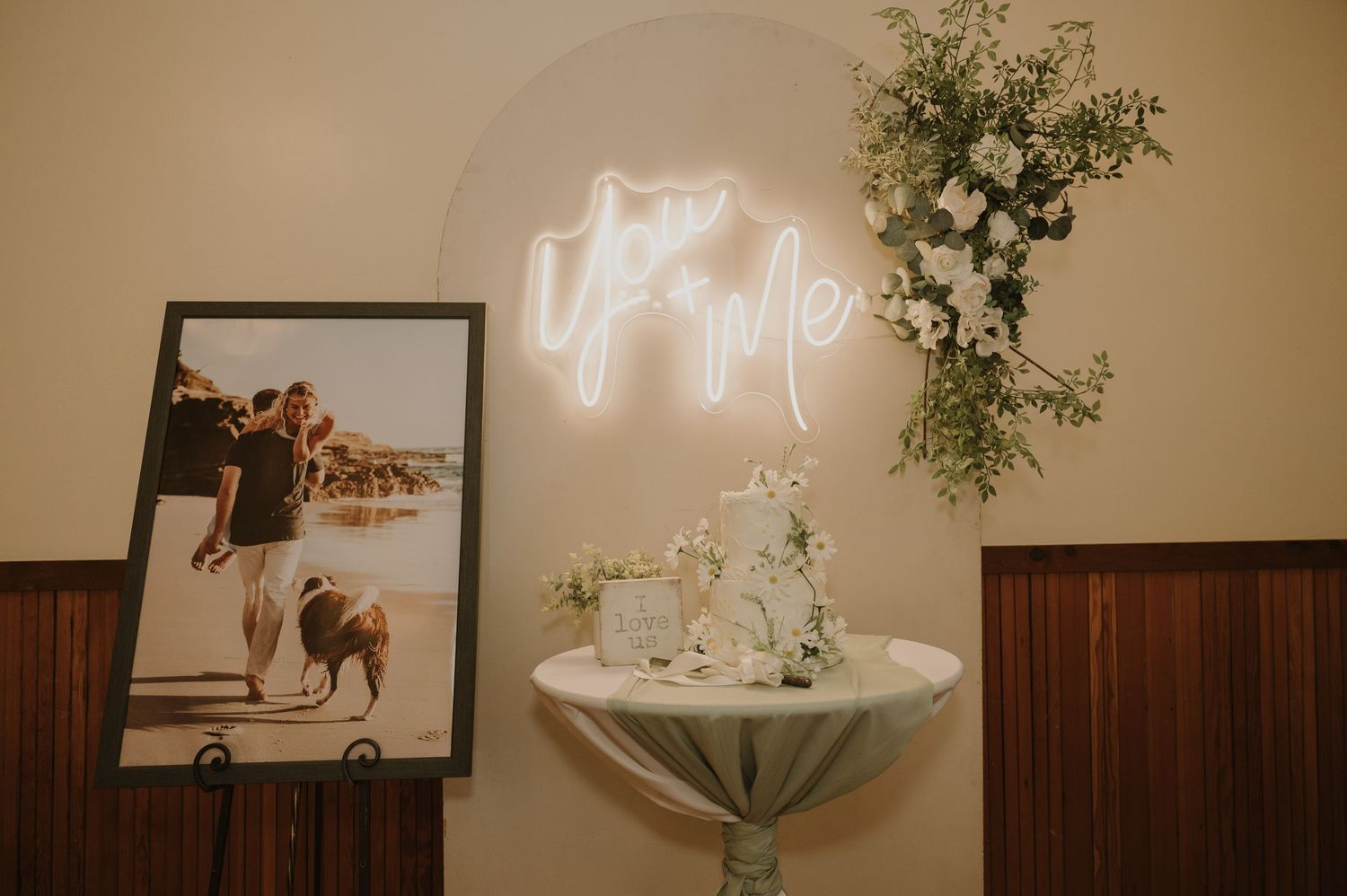 Wedding reception venue decorated with floral arrangements and neon signage.