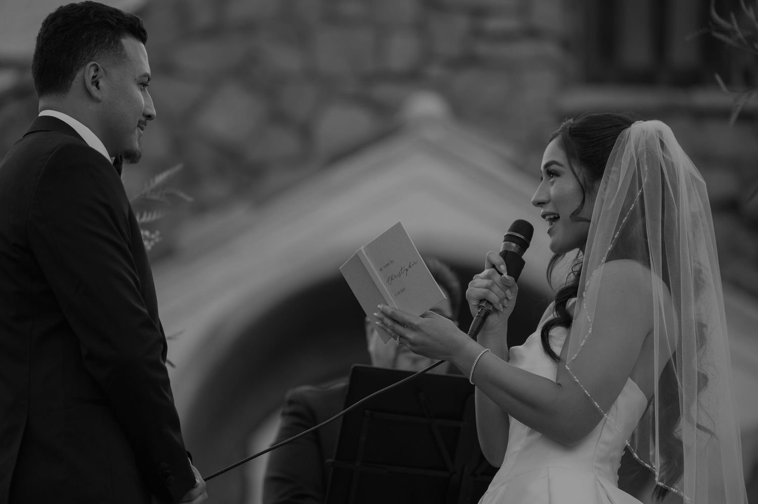 A wedding ceremony moment captured in black and white as vows are exchanged.