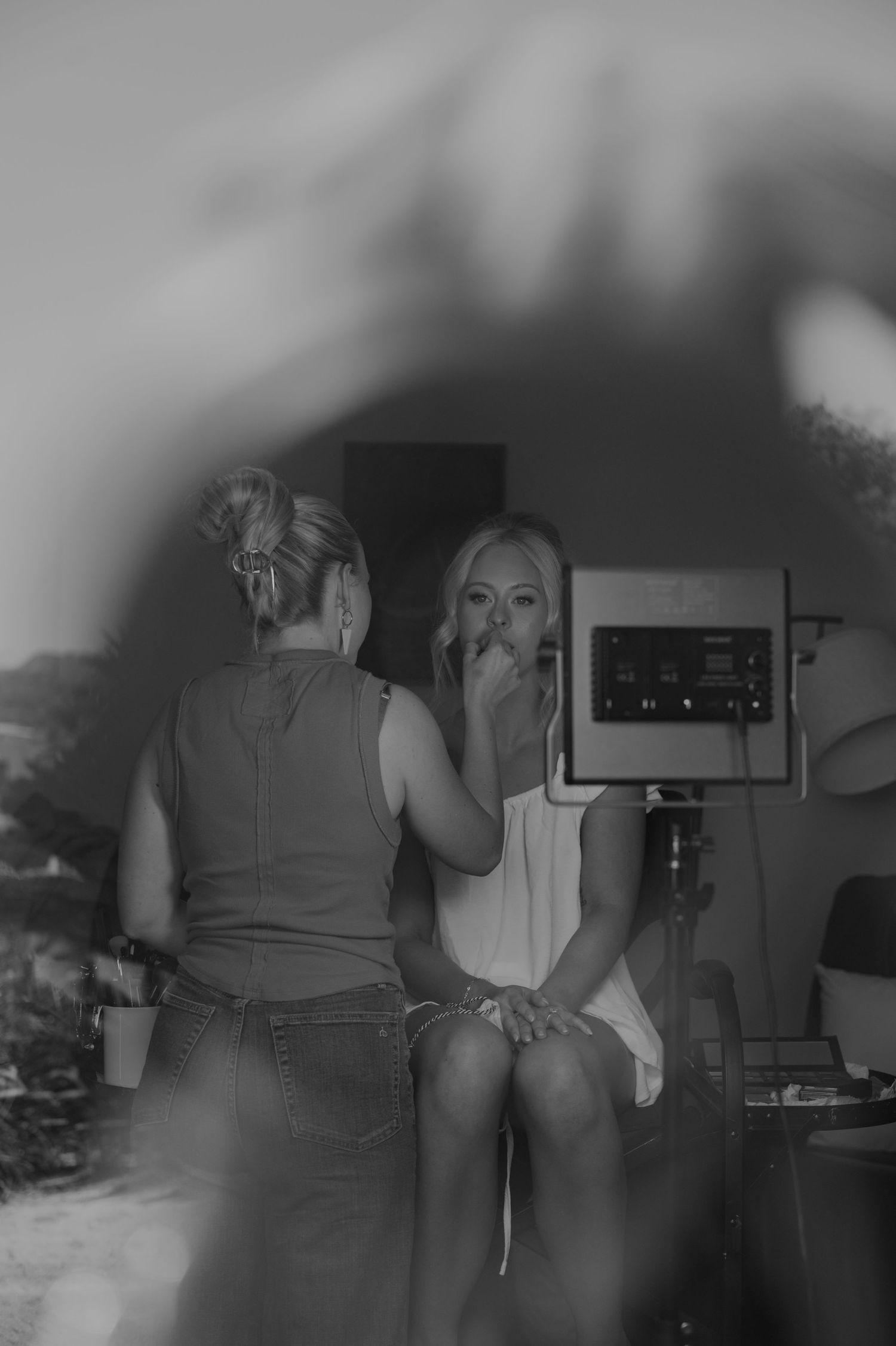 Black and white photo of a bride having her makeup applied before her wedding ceremony.